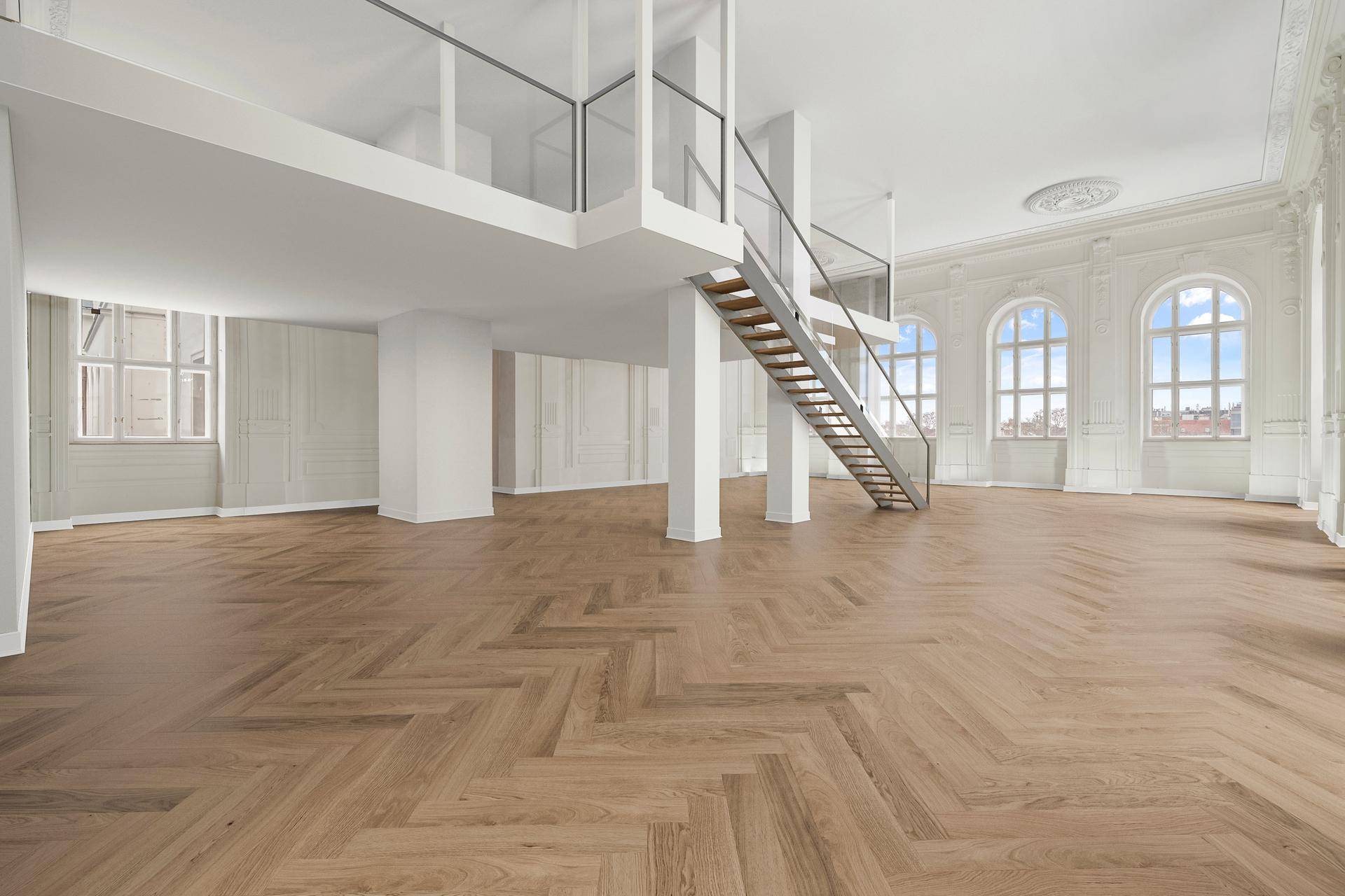 Geräumiger, leerer Wohnbereich mit elegantem Fischgrätparkett, hohen Decken und Zugang zur Galerie.