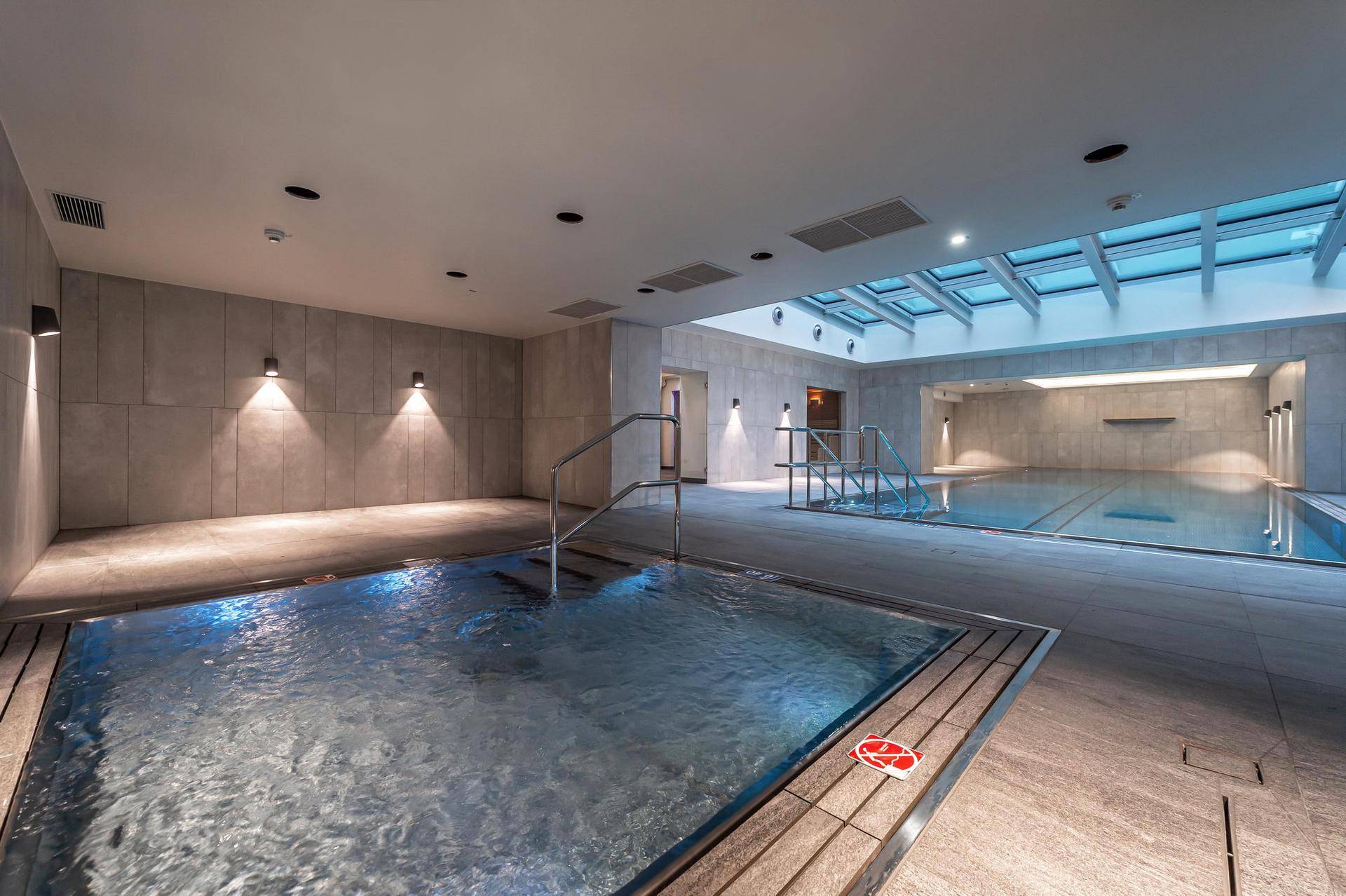 Wellnessbereich mit Innenpool, Whirlpool und natürlichem Licht durch das Glasdach.