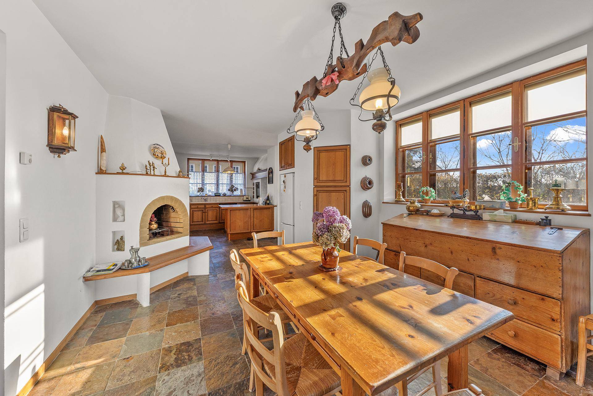 Rustikale Wohnküche mit Holztisch, Kamin und Schieferfliesenboden, ideal für gesellige Mahlzeiten.
