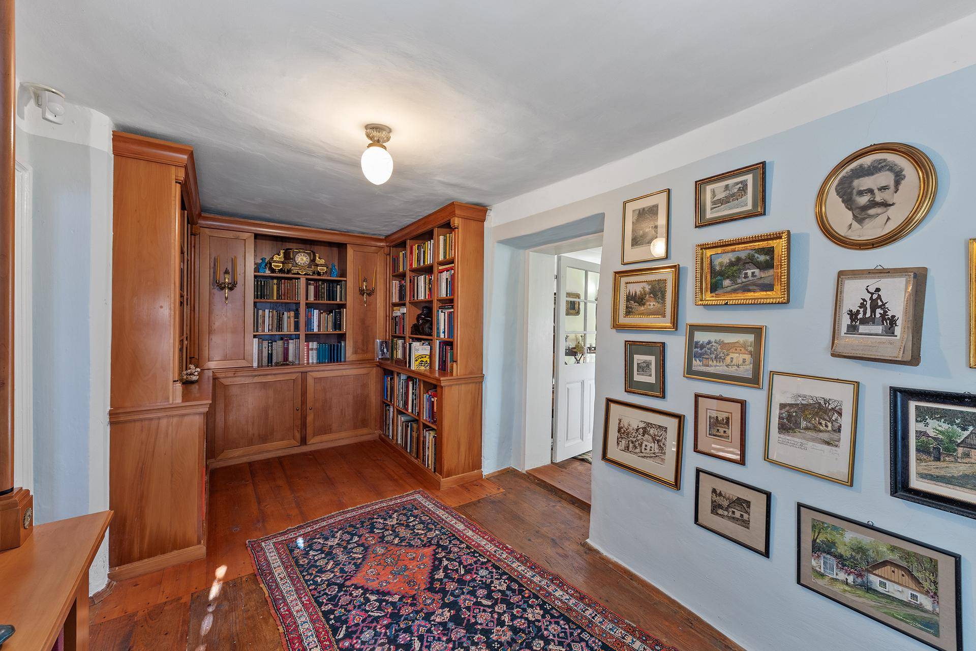 Gemütliche Bibliothek mit eingebauten Holzregalen, vielen Büchern und einem traditionellen Teppich.