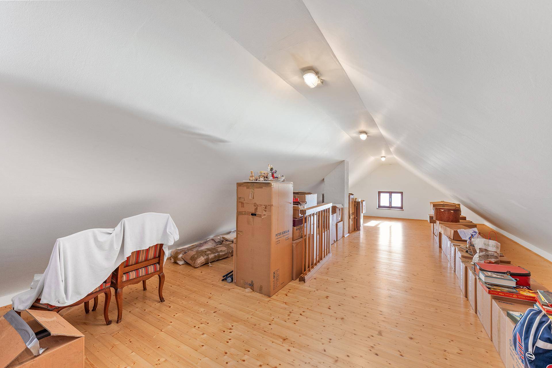 Geräumiger Dachboden mit Holzboden und gelagerten Gegenständen, ideal als Abstellraum.
