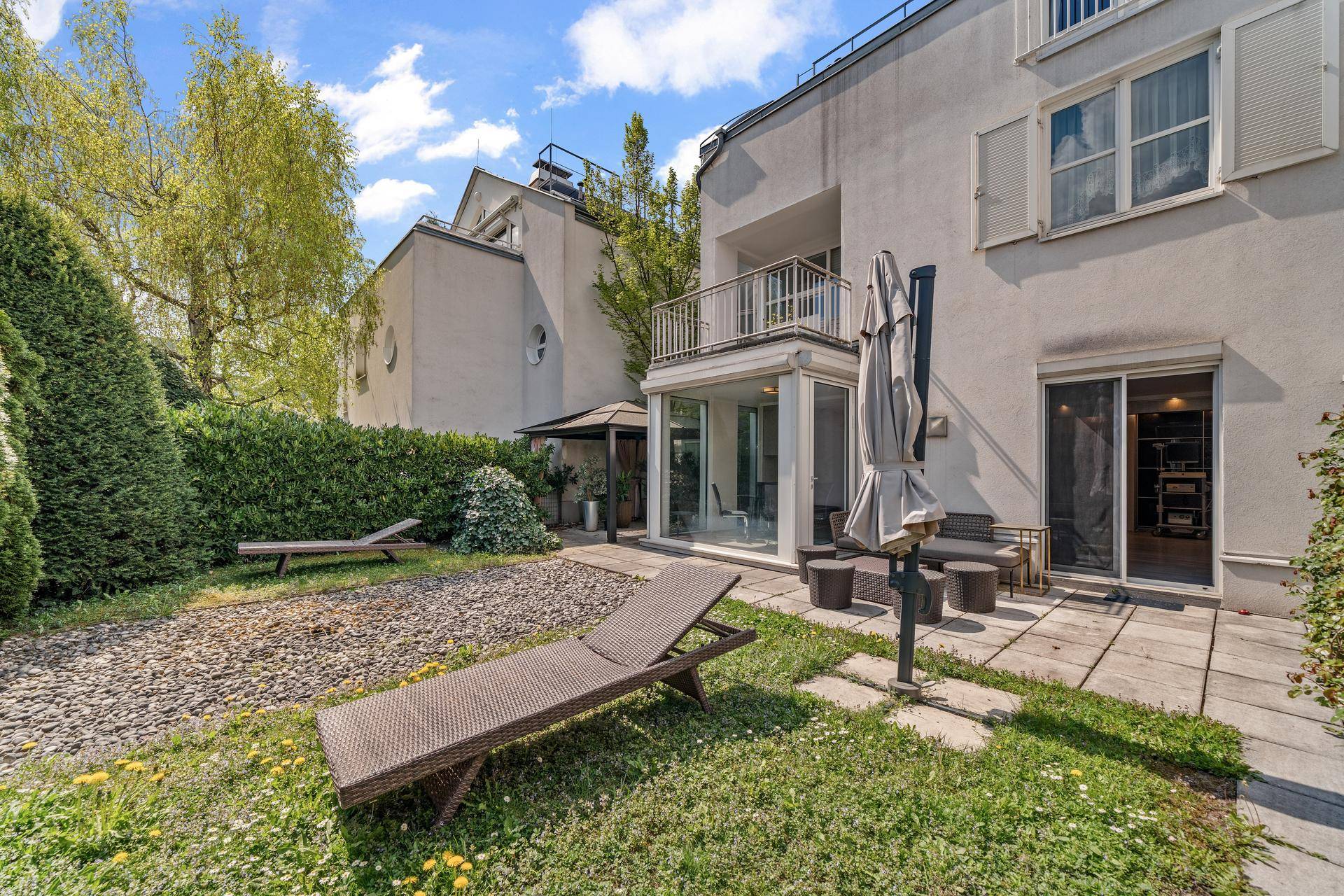 Gepflegter Gartenbereich mit Terrasse, Liegestühlen und üppiger Bepflanzung.