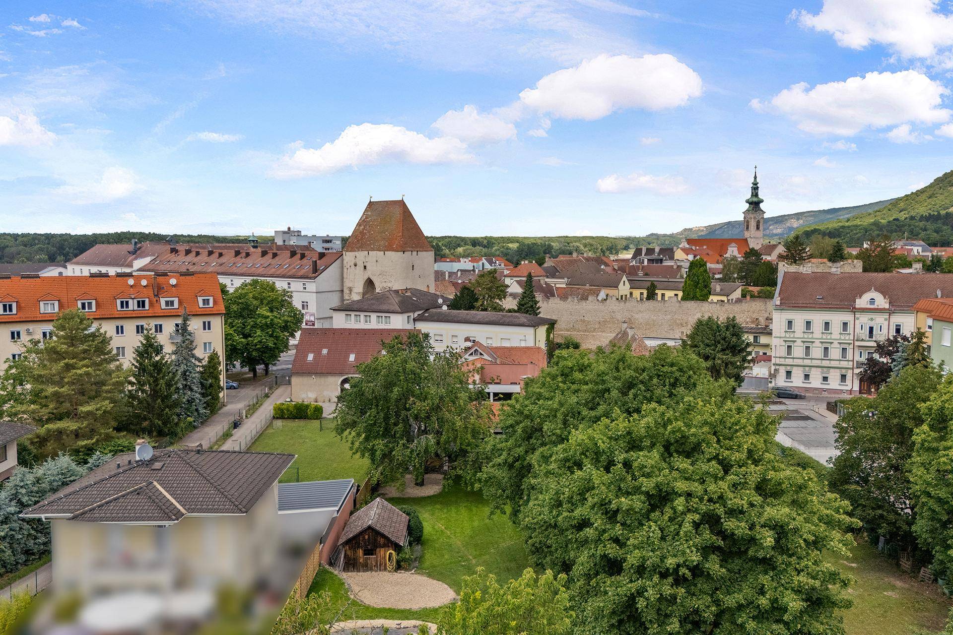 Panoramablick auf eine historische Stadt mit Kirchturm und grüner Umgebung.