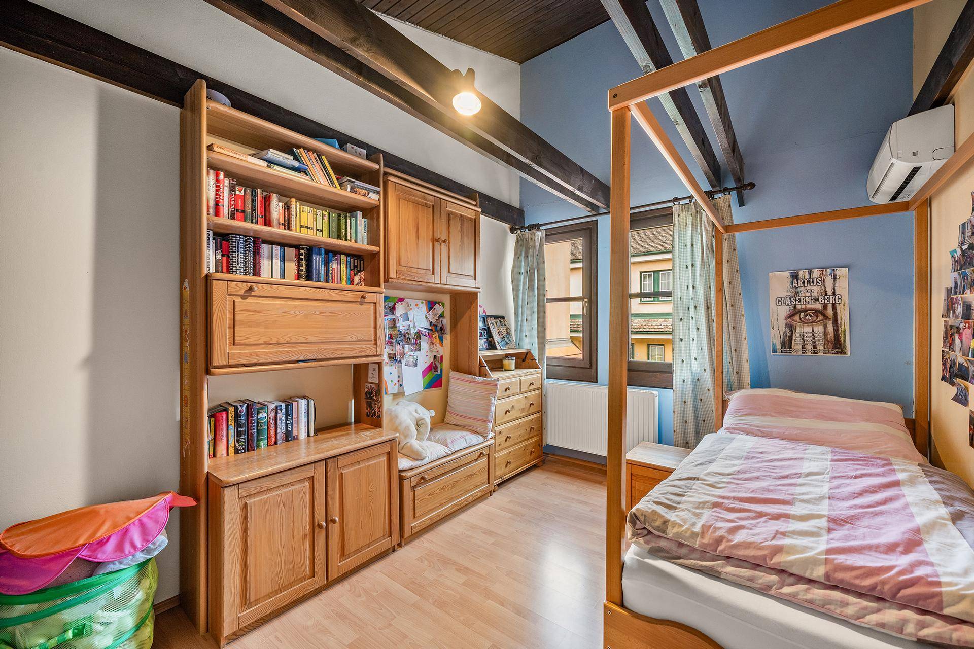 Kinderzimmer mit Himmelbett, Holzbalken und integrierten Holzschränken.