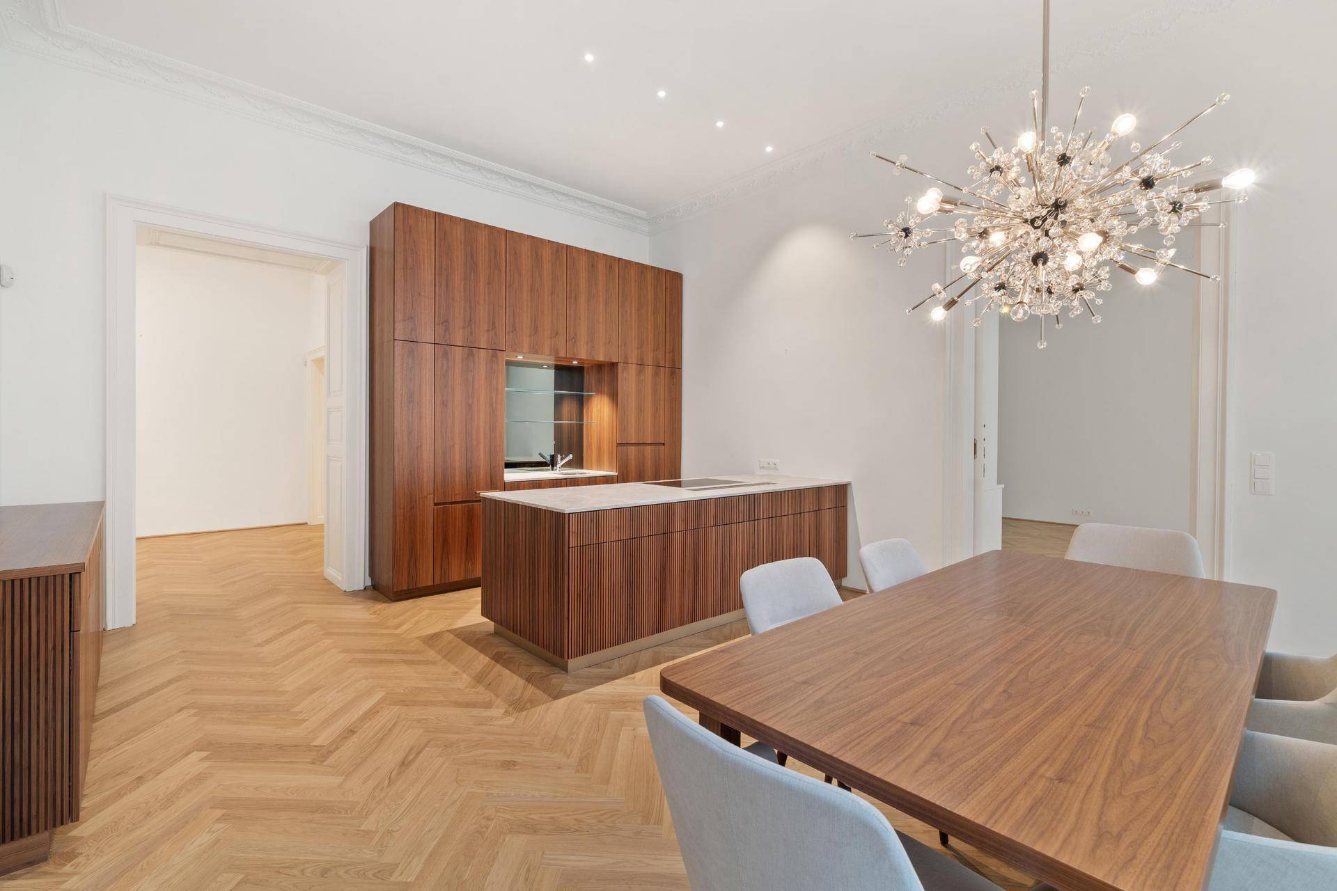 Moderner offener Wohn-Essbereich mit Holzküche, Kücheninsel und elegantem Fischgrätparkett.