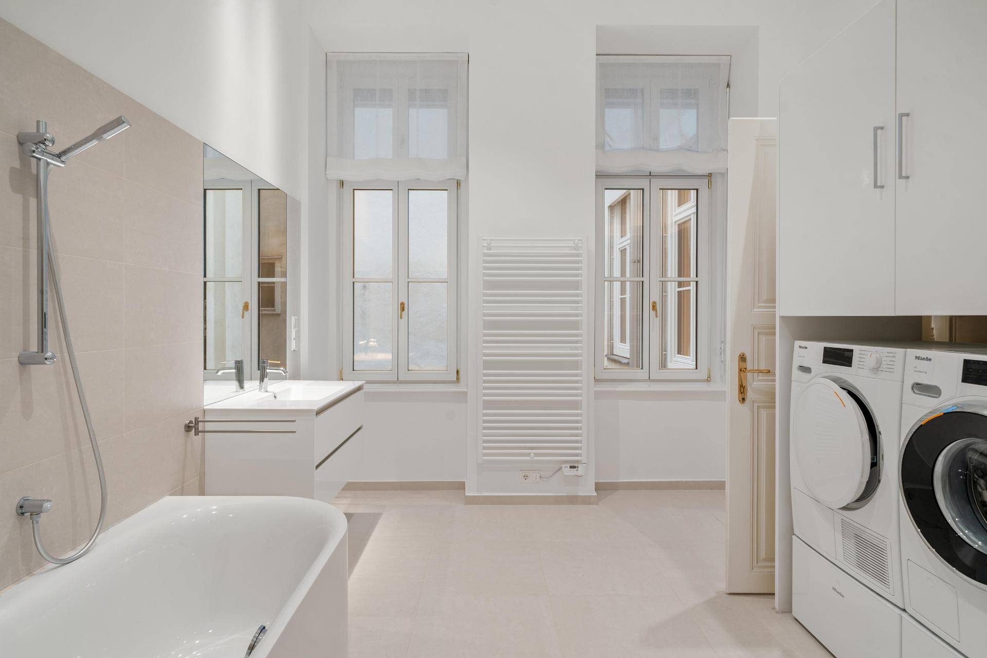 Modernes Badezimmer mit Badewanne, Waschmaschine, Trockner und beheiztem Handtuchhalter.