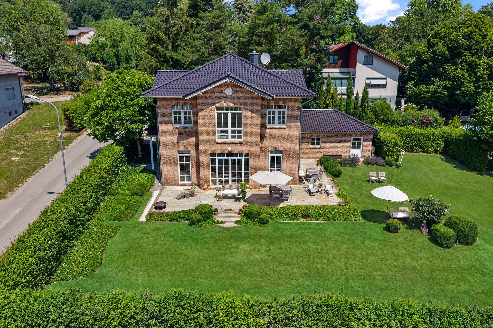 Luftaufnahme des Backsteinhauses mit großem Garten, Terrasse und umliegender grüner Landschaft.
