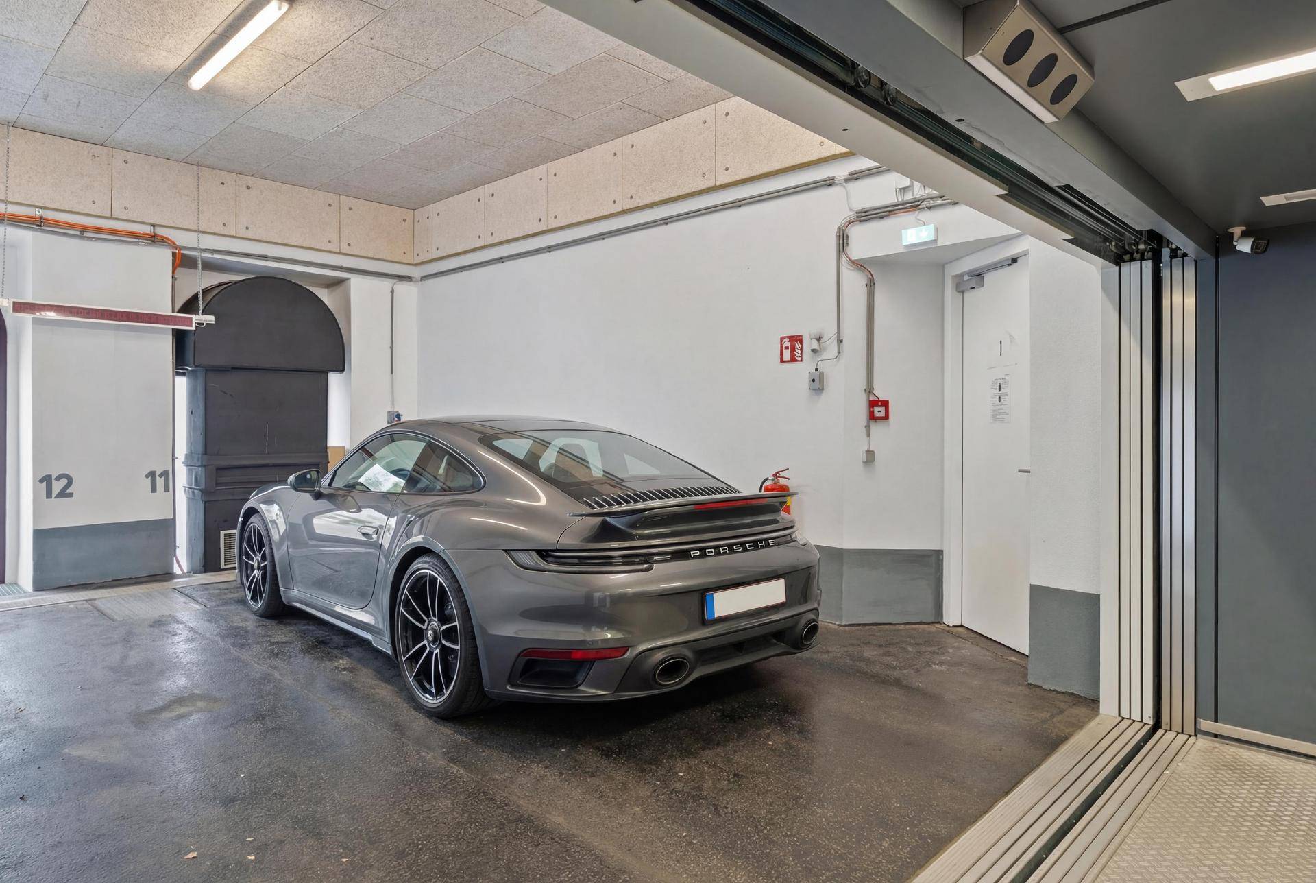 Tiefgarage mit einem Luxusauto und nummerierten Stellplätzen.