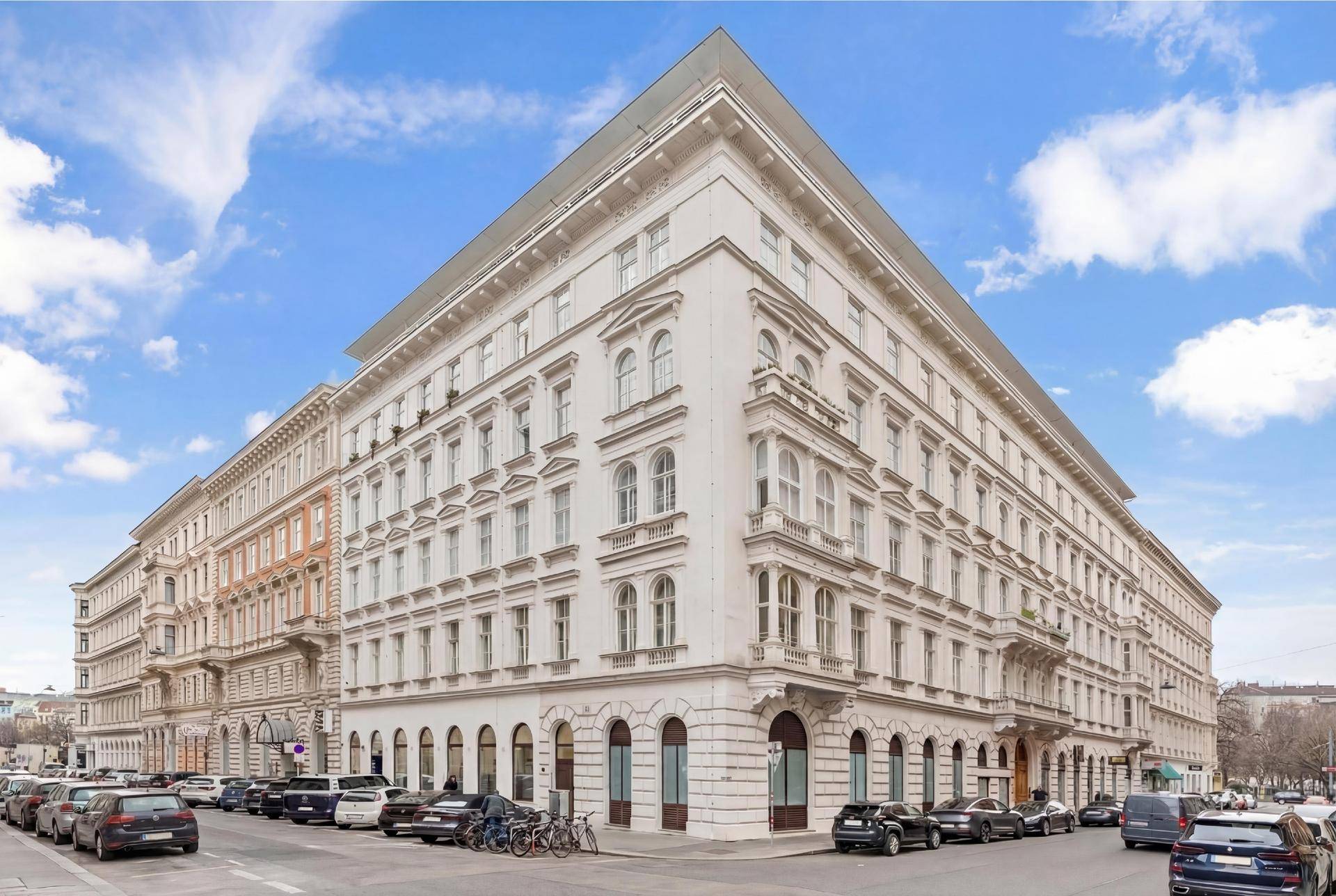 Prächtiges Eckgebäude mit klassischer Architektur und vielen Fenstern an einer Stadtstraße.
