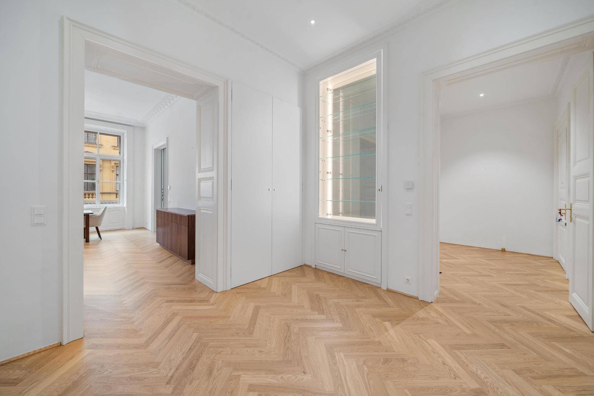 Eleganter Flur mit Fischgrätparkett und integrierter Vitrine, verbindet verschiedene Räume.