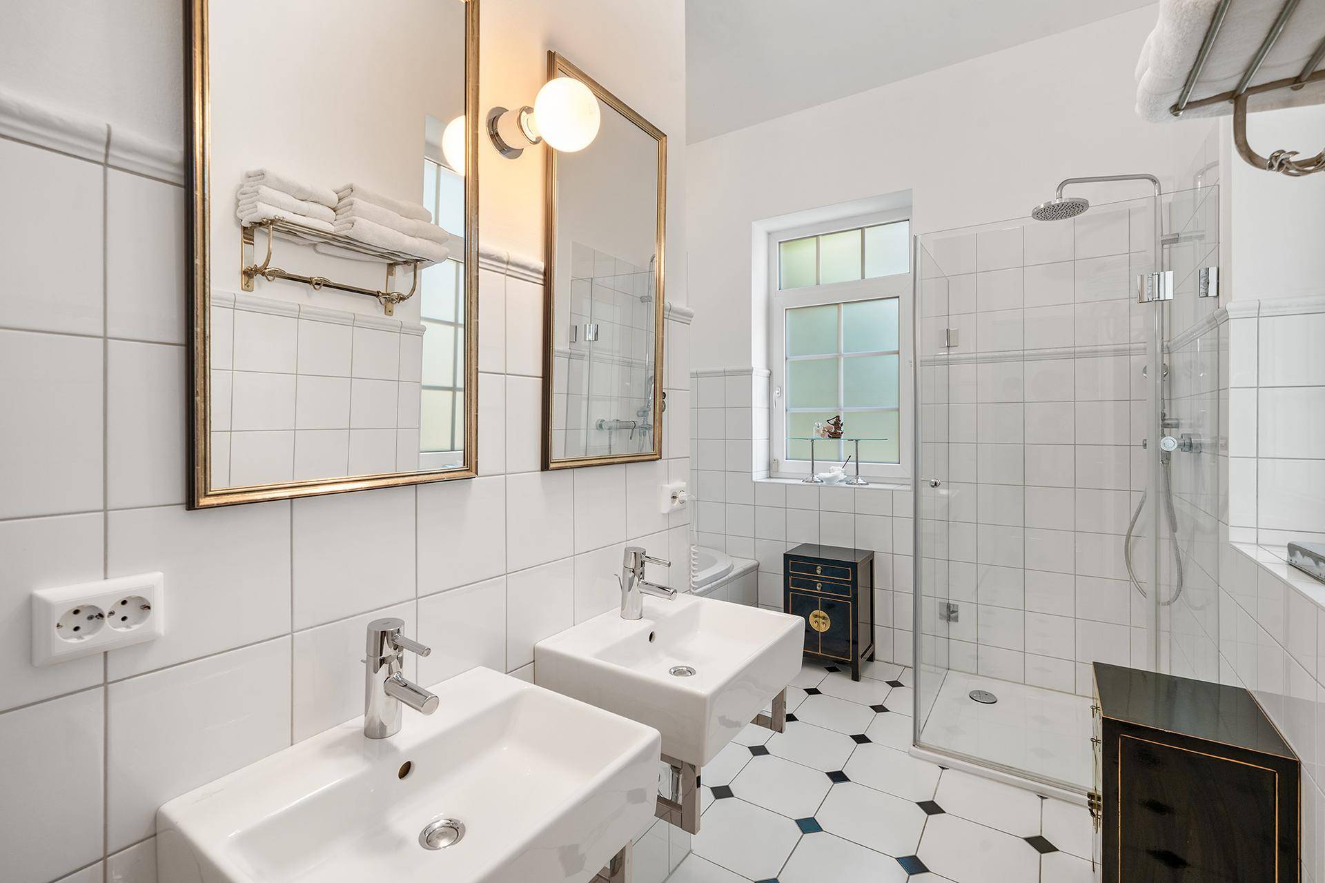Modernes Badezimmer mit zwei Waschbecken, großer begehbarer Dusche und weißen Fliesen.