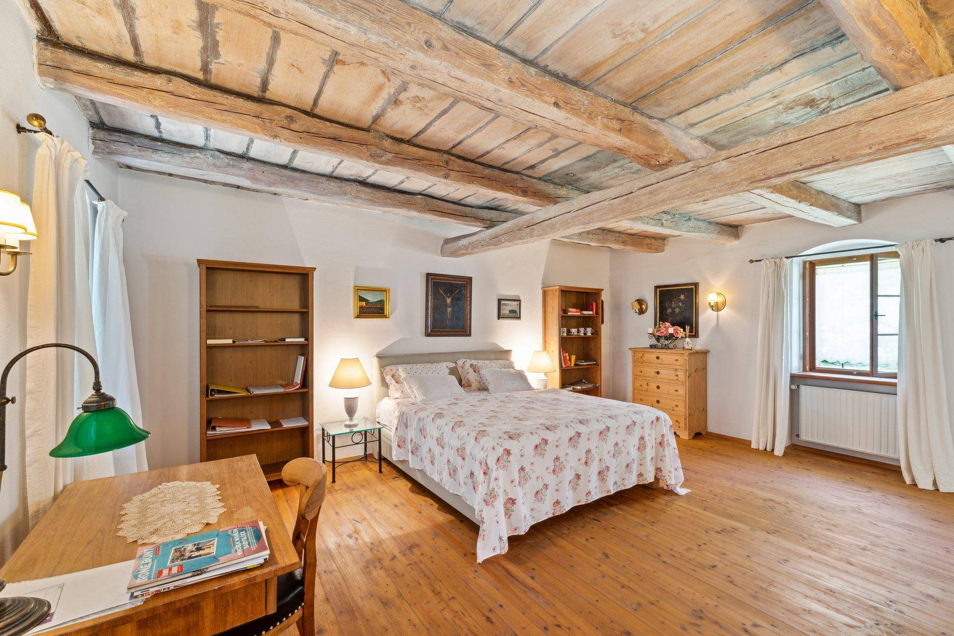 Geräumiges Schlafzimmer mit freiliegenden Holzbalken, Holzboden und traditioneller Einrichtung.