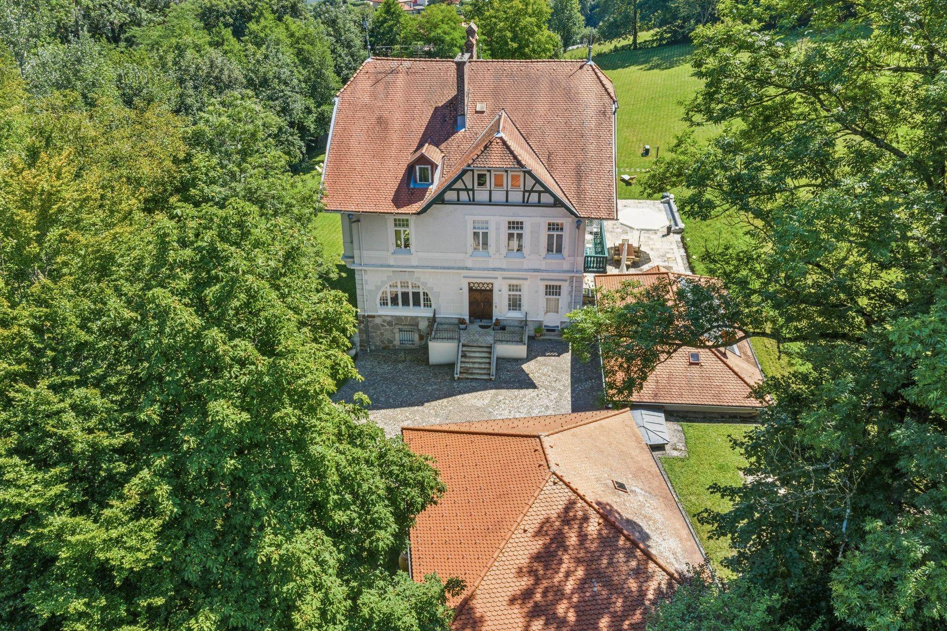 Vogelperspektive der Villa mit rotem Dach, umgeben von üppigem Grün und Bäumen.