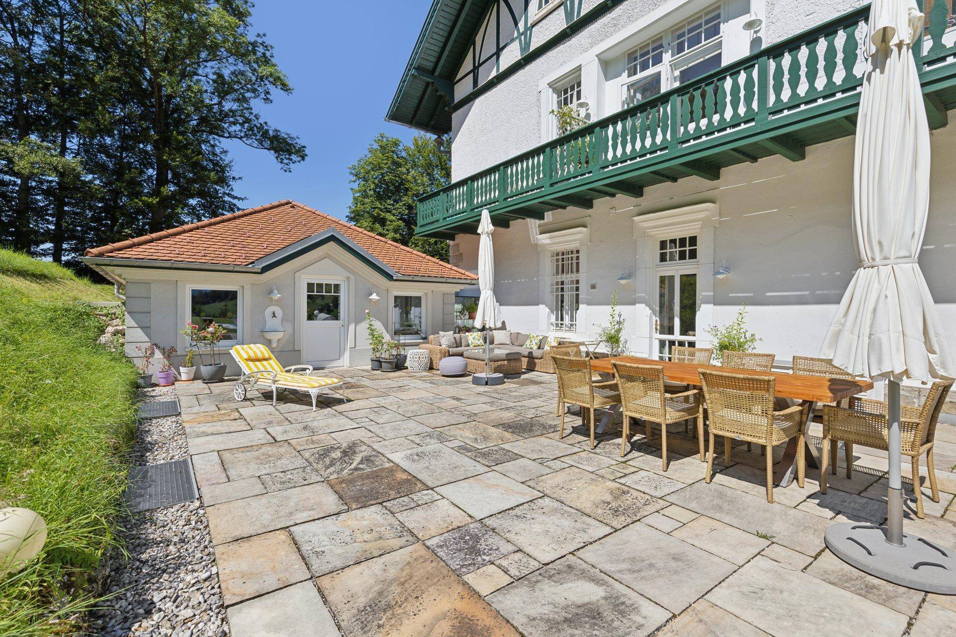 Große, gepflasterte Terrasse mit Essbereich und Lounge-Möbeln, ideal für Entspannung im Freien.