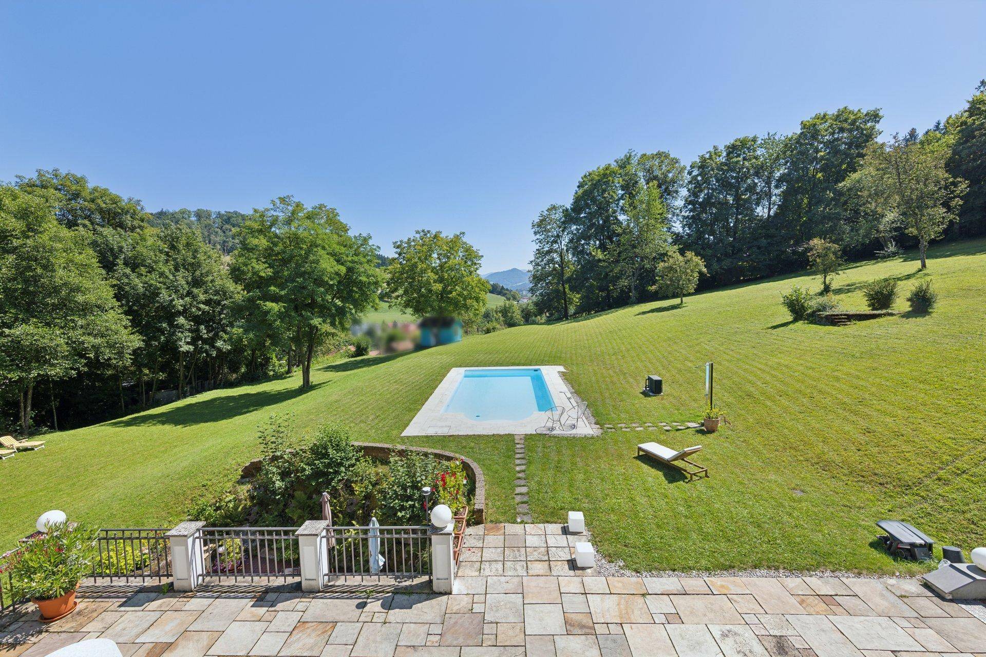 Weitläufiger Gartenbereich mit einem erfrischenden Pool und Liegewiese in sonniger Lage.