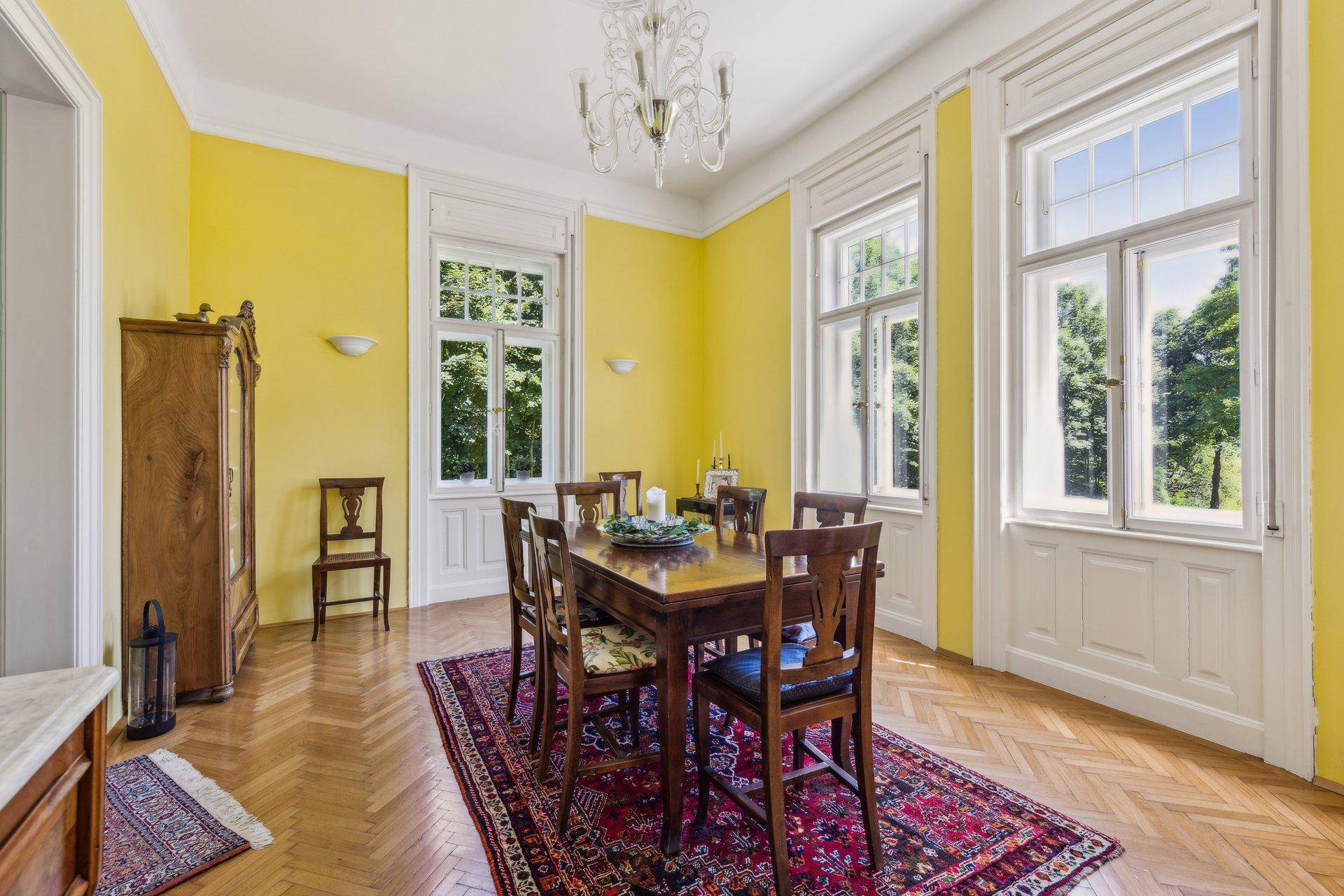 Stilvolles Esszimmer mit gelben Wänden, Holztisch und Parkettboden, ideal für gesellige Runden.