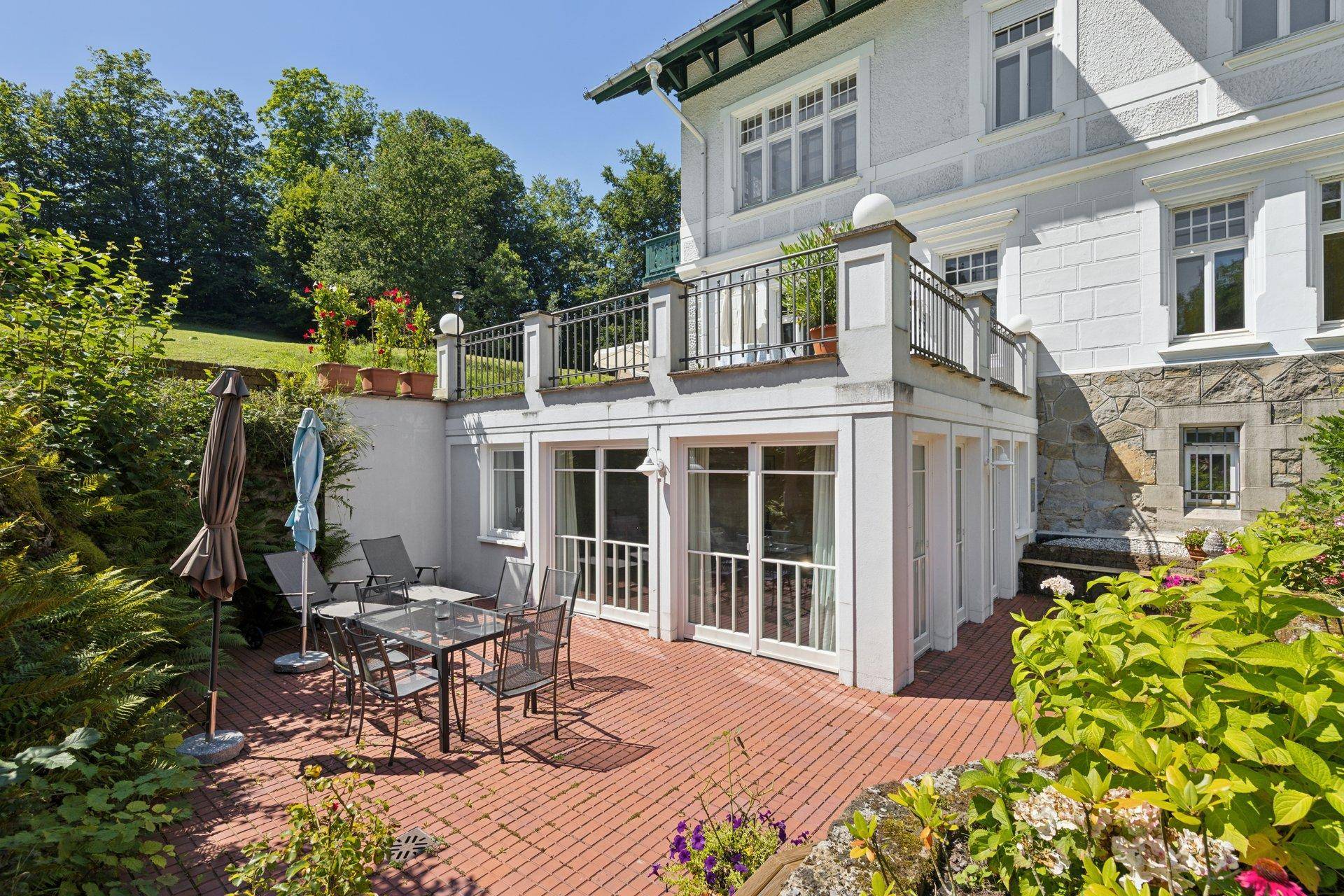 Gemütliche Terrasse mit Sitzgelegenheiten und Blick auf den grünen Gartenbereich.