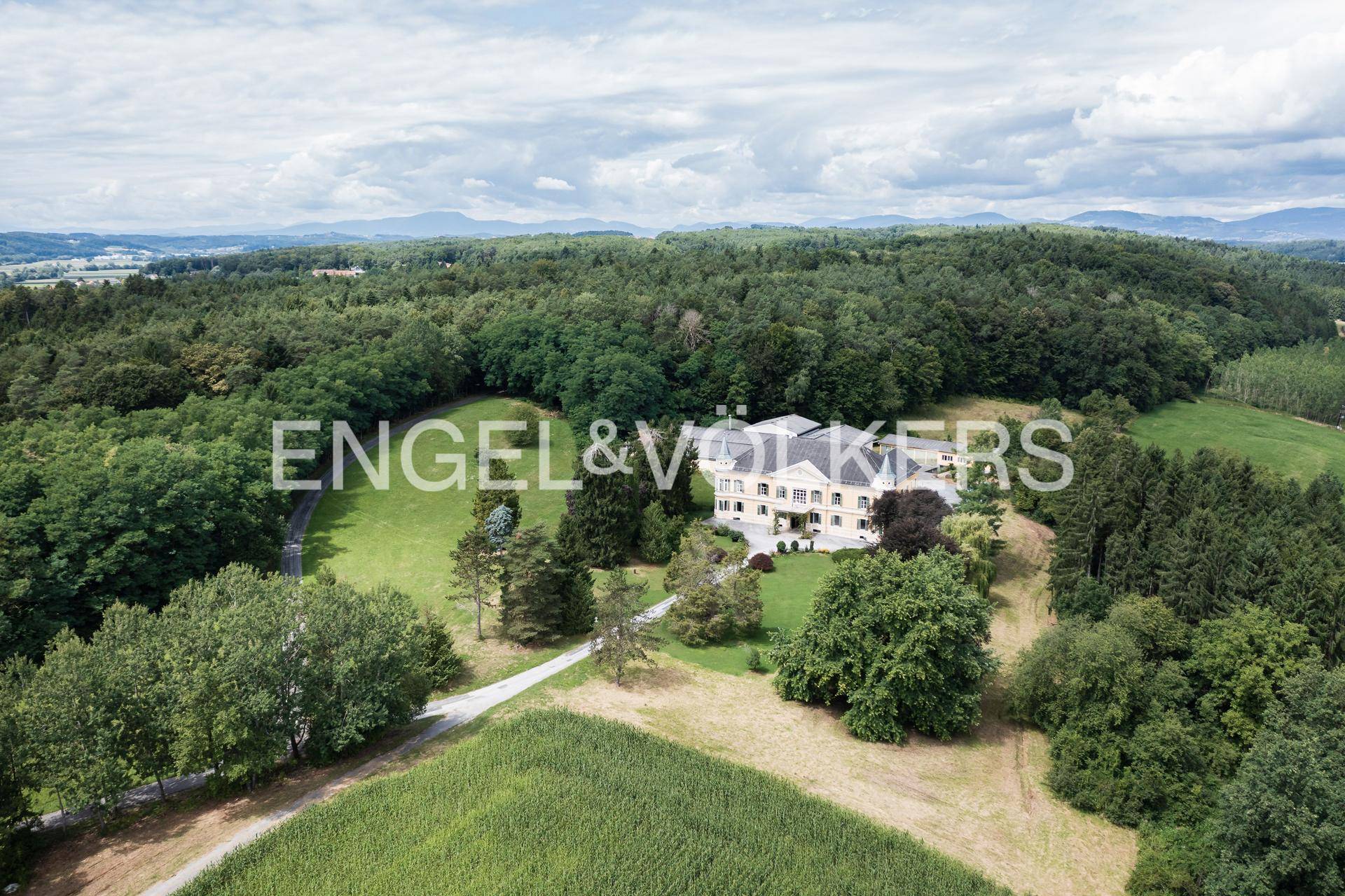 Panoramablick auf das weitläufige Anwesen, eingebettet in eine grüne Hügellandschaft.