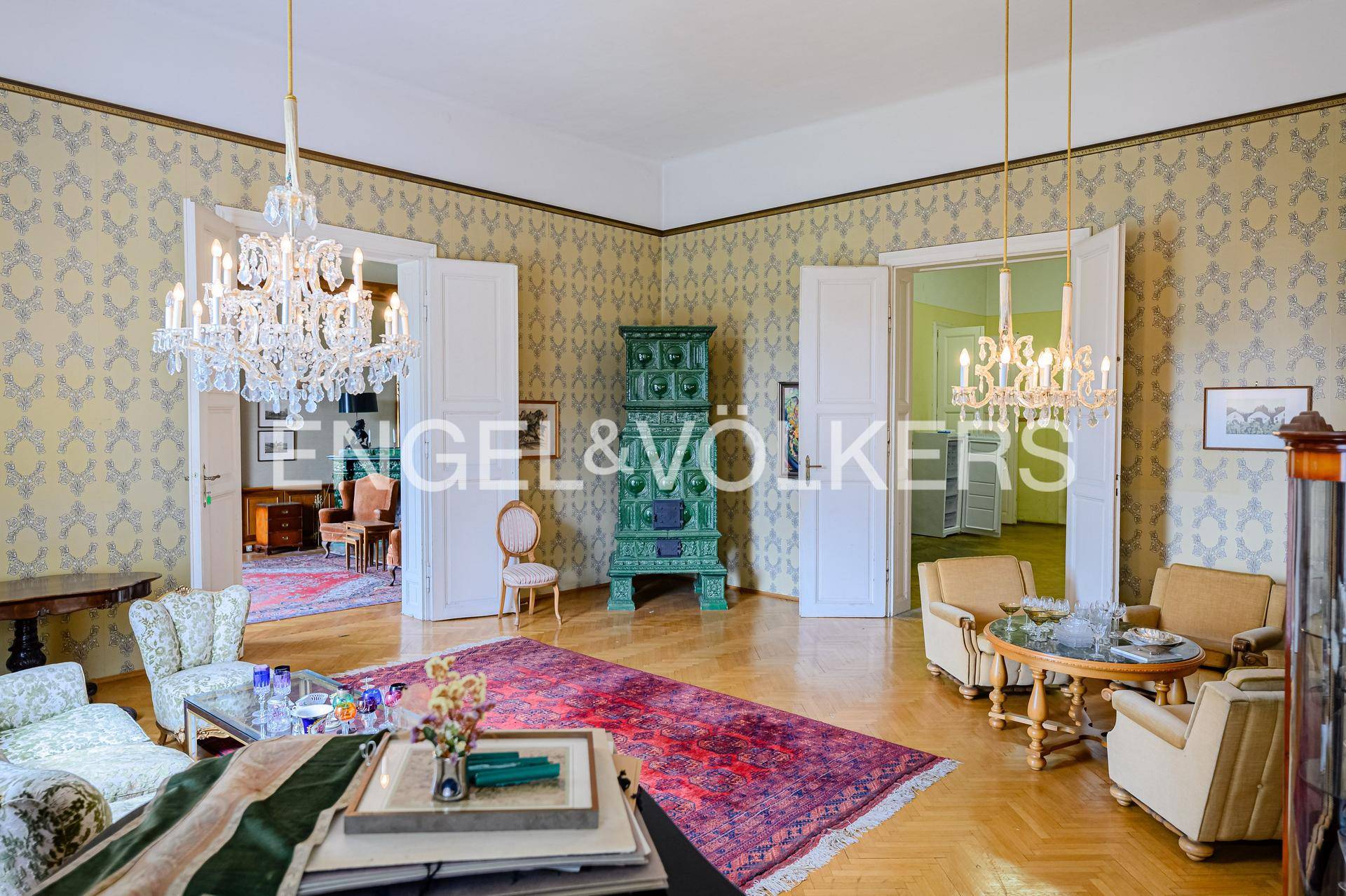 Repräsentatives Wohnzimmer mit Parkettboden, Kronleuchtern und einem traditionellen Kachelofen.