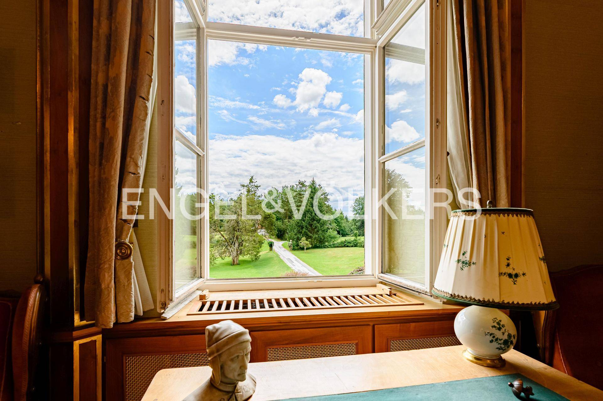 Arbeitszimmer mit Blick ins Grüne durch ein großes Fenster, das viel Tageslicht hereinlässt.