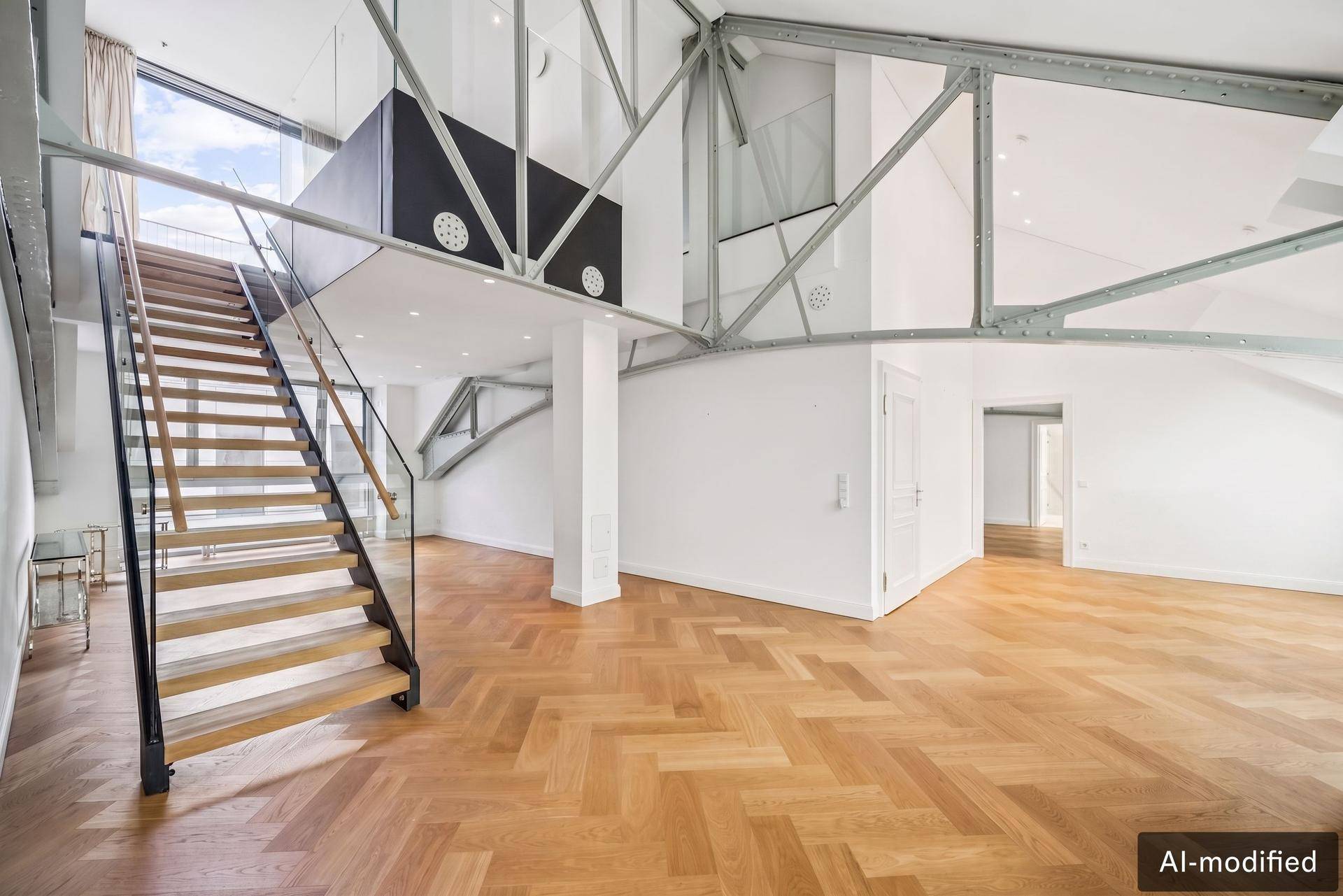 Heller Eingangsbereich mit moderner Holztreppe, Glasgeländer und hohen Decken.