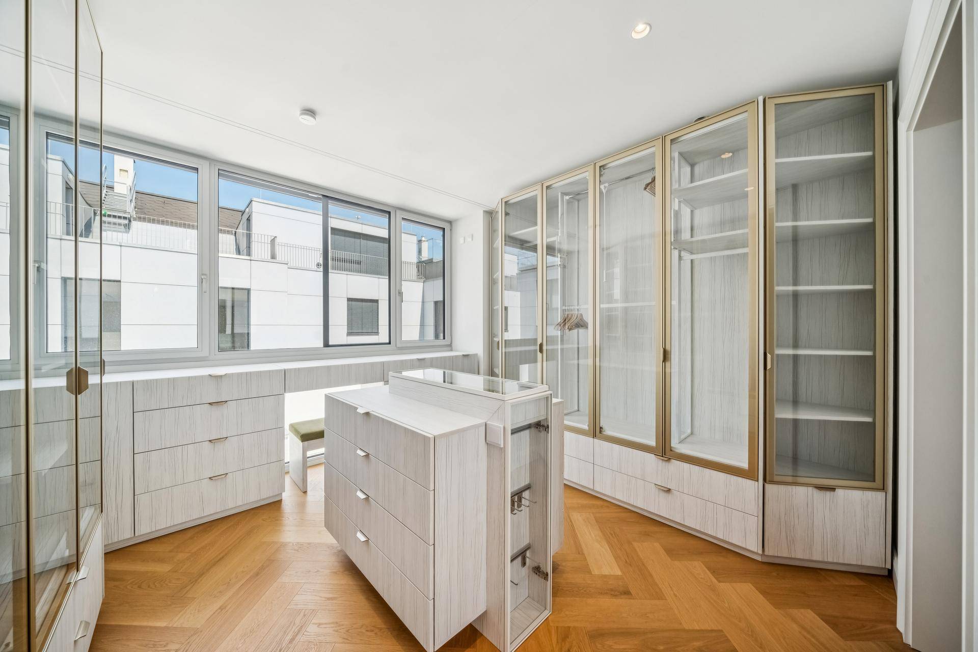 Geräumiger begehbarer Kleiderschrank mit Einbauschränken und großen Fenstern.