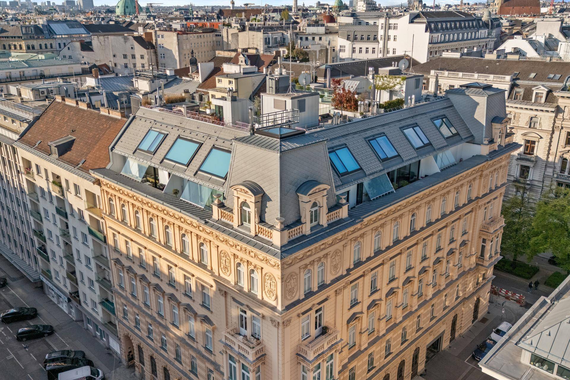 Luftaufnahme des historischen Gebäudes mit moderner Dachkonstruktion und Blick auf die Stadt.