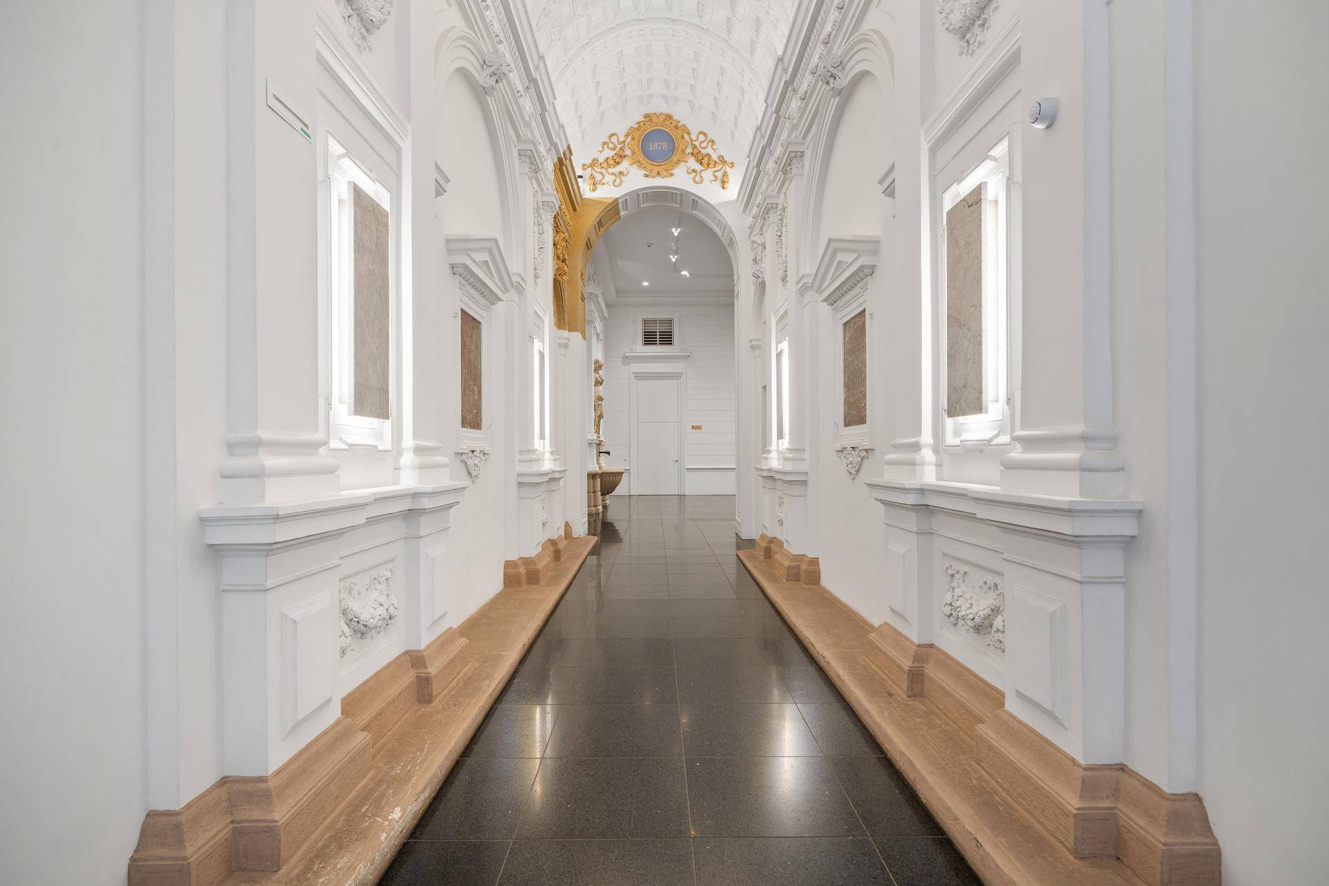 Historischer Flur mit gewölbten Decken, dunklem Fliesenboden und klassischen architektonischen Details.