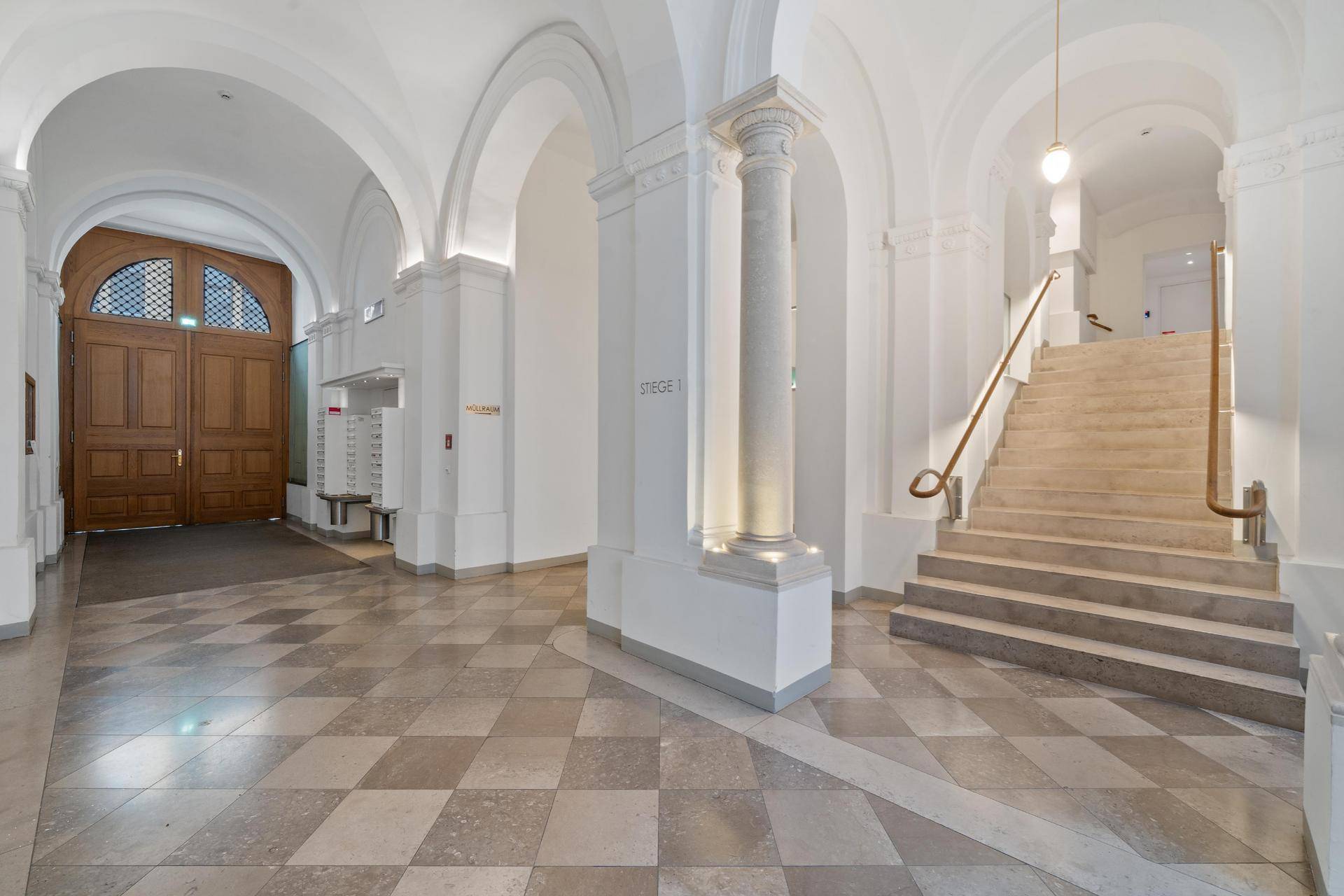 Repräsentativer Eingangsbereich mit hohen Gewölben, Säulen und einer breiten Treppe.