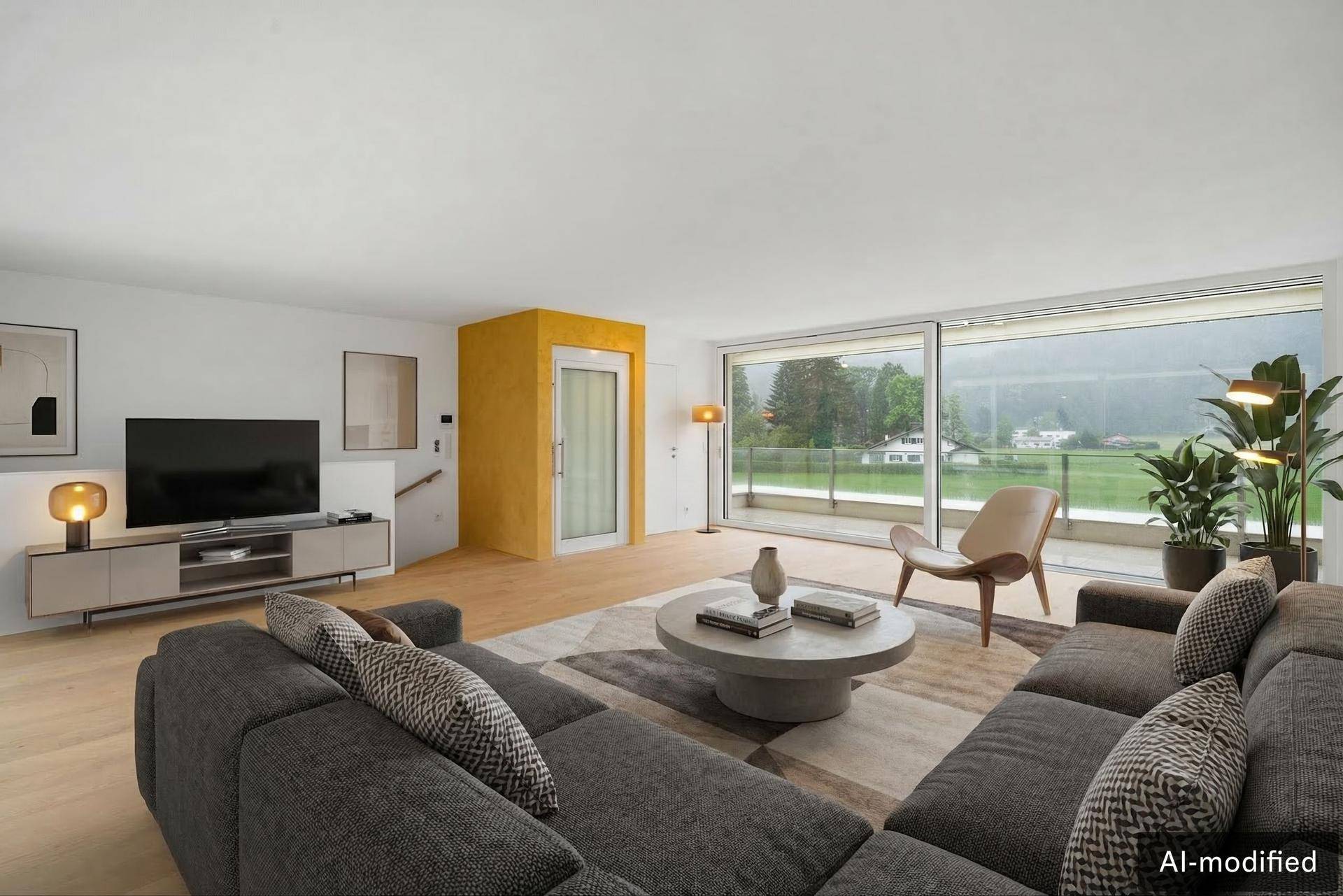 Helles Wohnzimmer mit großem Sofa, Holzboden und Zugang zu einem Balkon mit Bergblick.