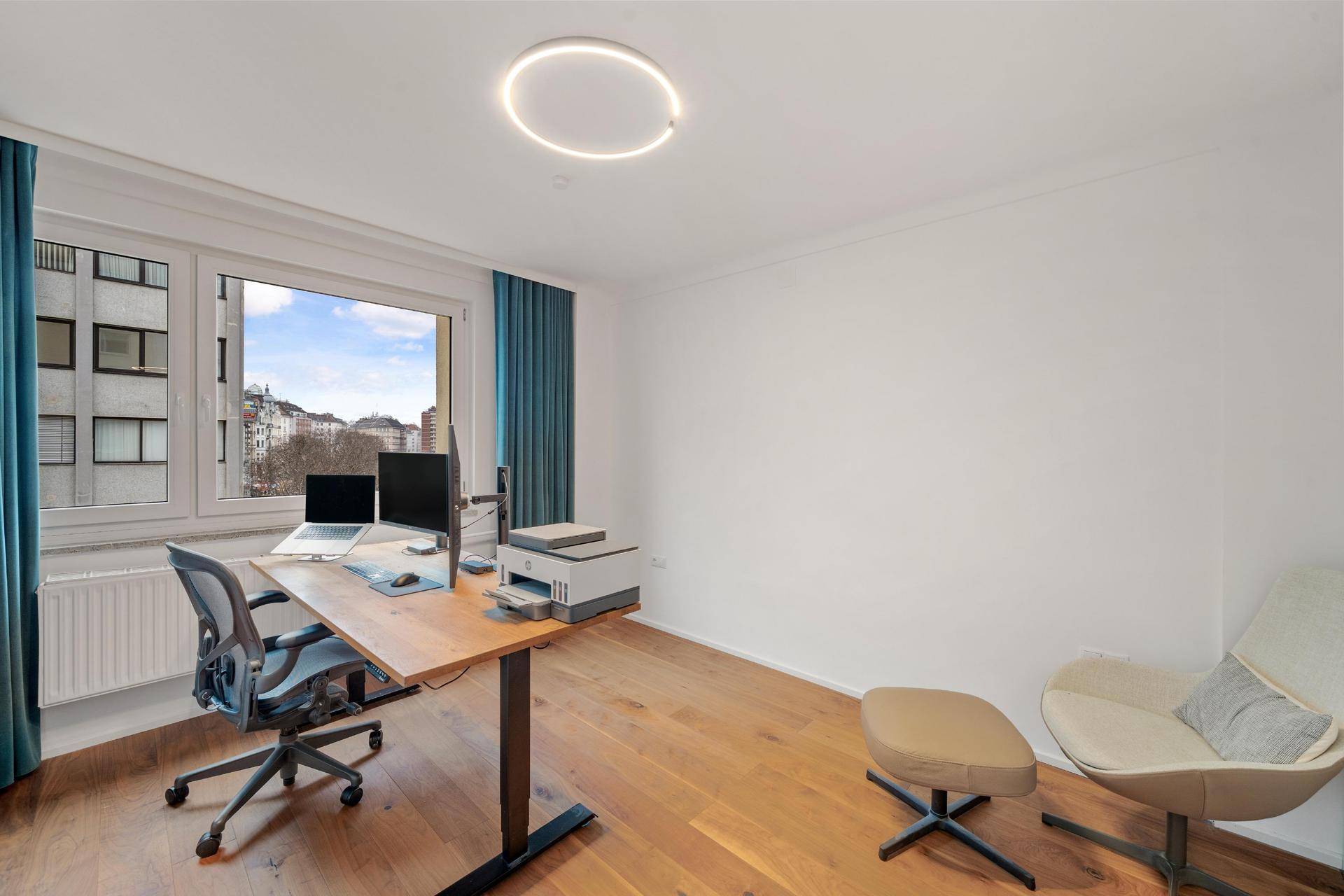 Helles Arbeitszimmer mit großem Schreibtisch, Bürostuhl und Blick auf die Stadt.