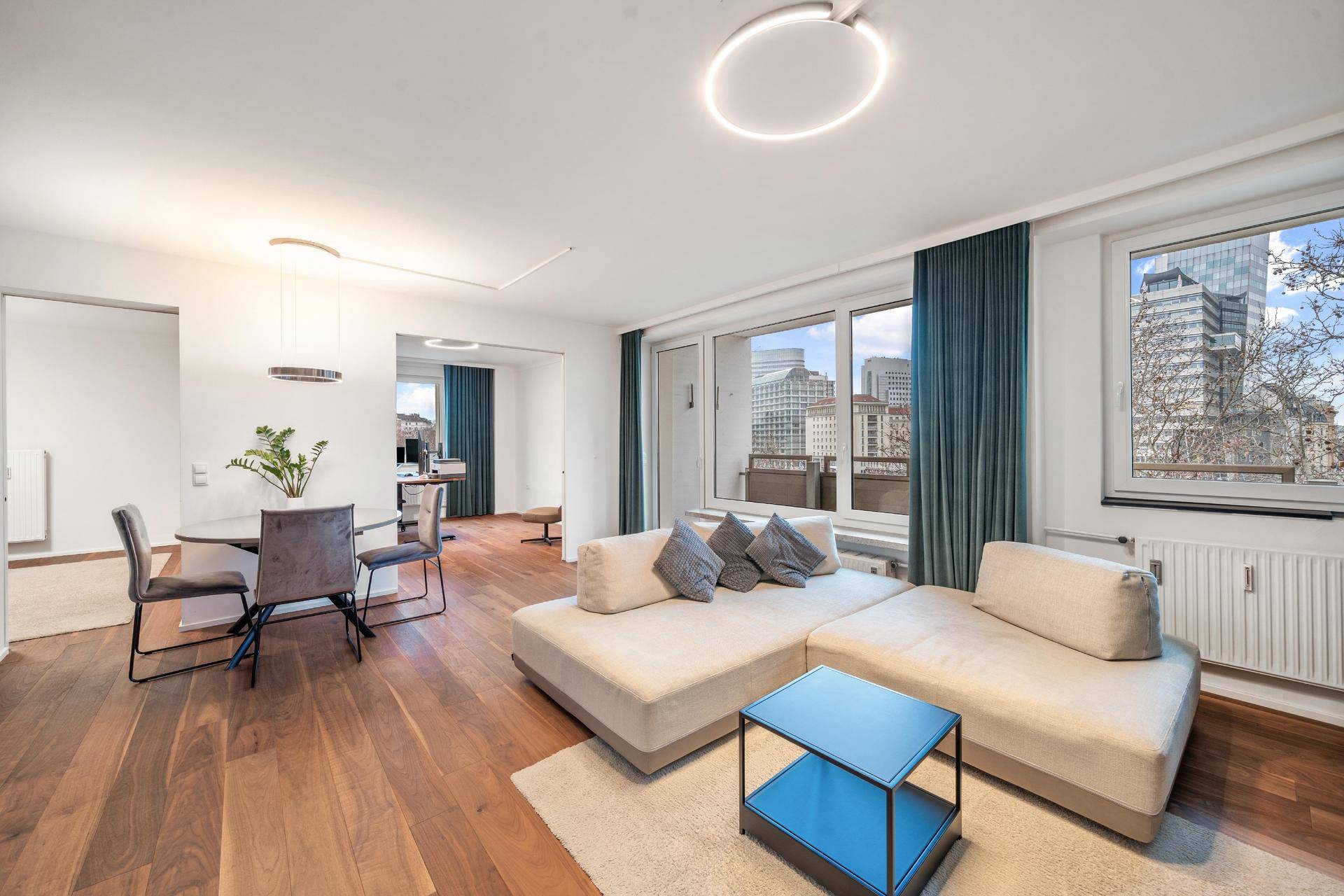 Heller Wohn-Essbereich mit Holzboden, bequemer Couch und Blick auf die Stadt.