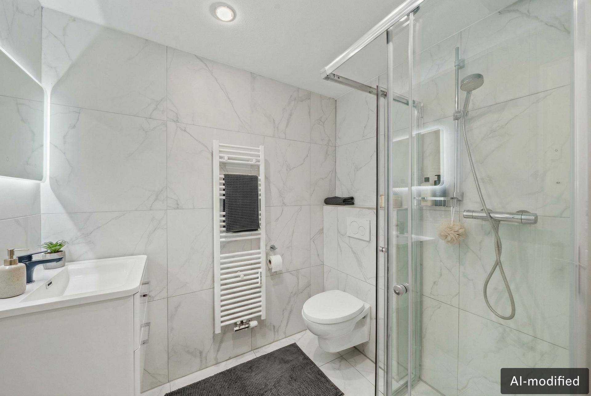 Elegantes Badezimmer mit moderner Dusche, WC und Waschtisch, ausgestattet mit Marmorfliesen.