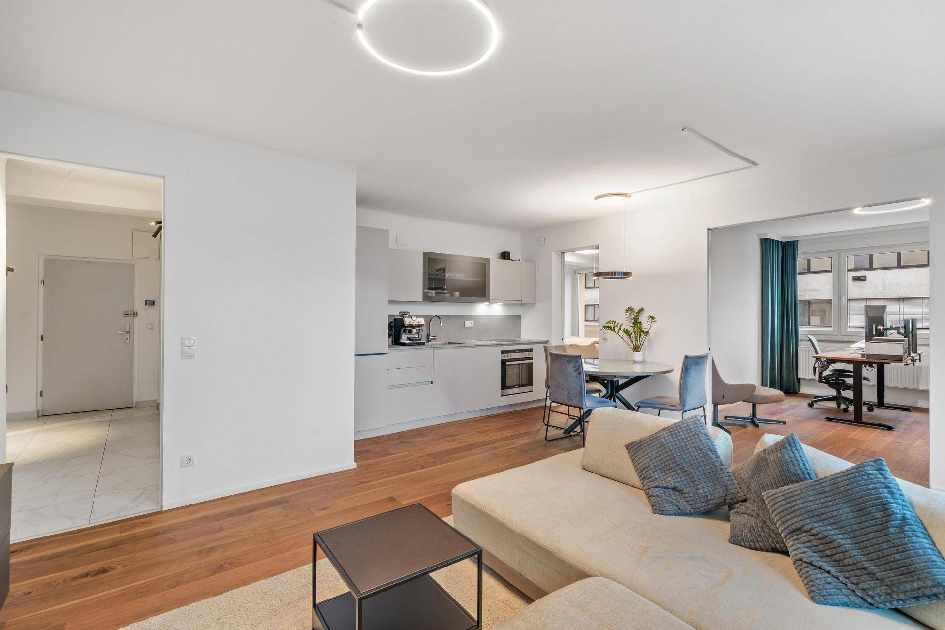 Offener Wohnbereich kombiniert Küche, Ess- und Wohnzimmer, mit Holzboden und moderner Einrichtung.