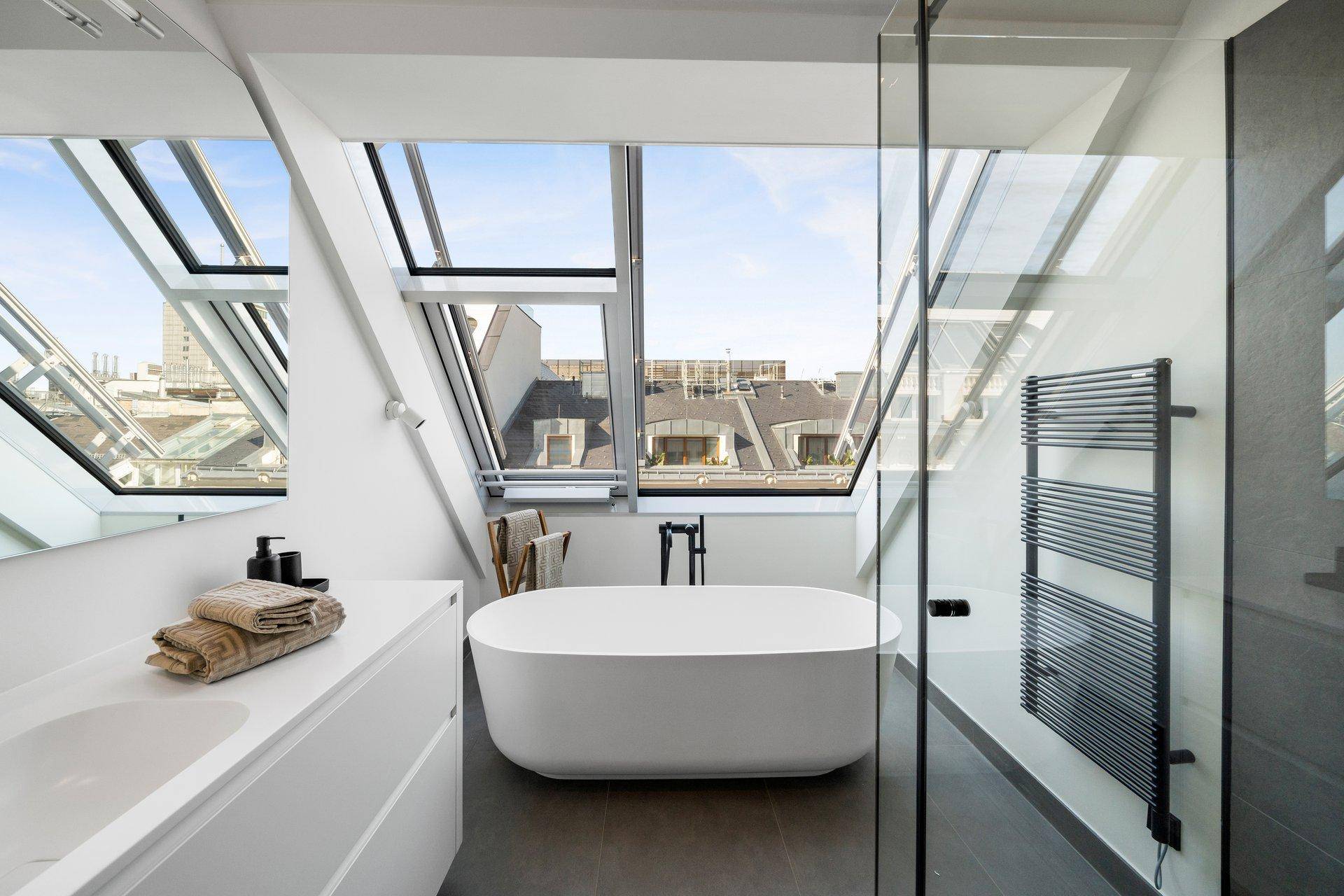 Modernes Badezimmer mit freistehender Badewanne, begehbarer Dusche und weitem Stadtblick.