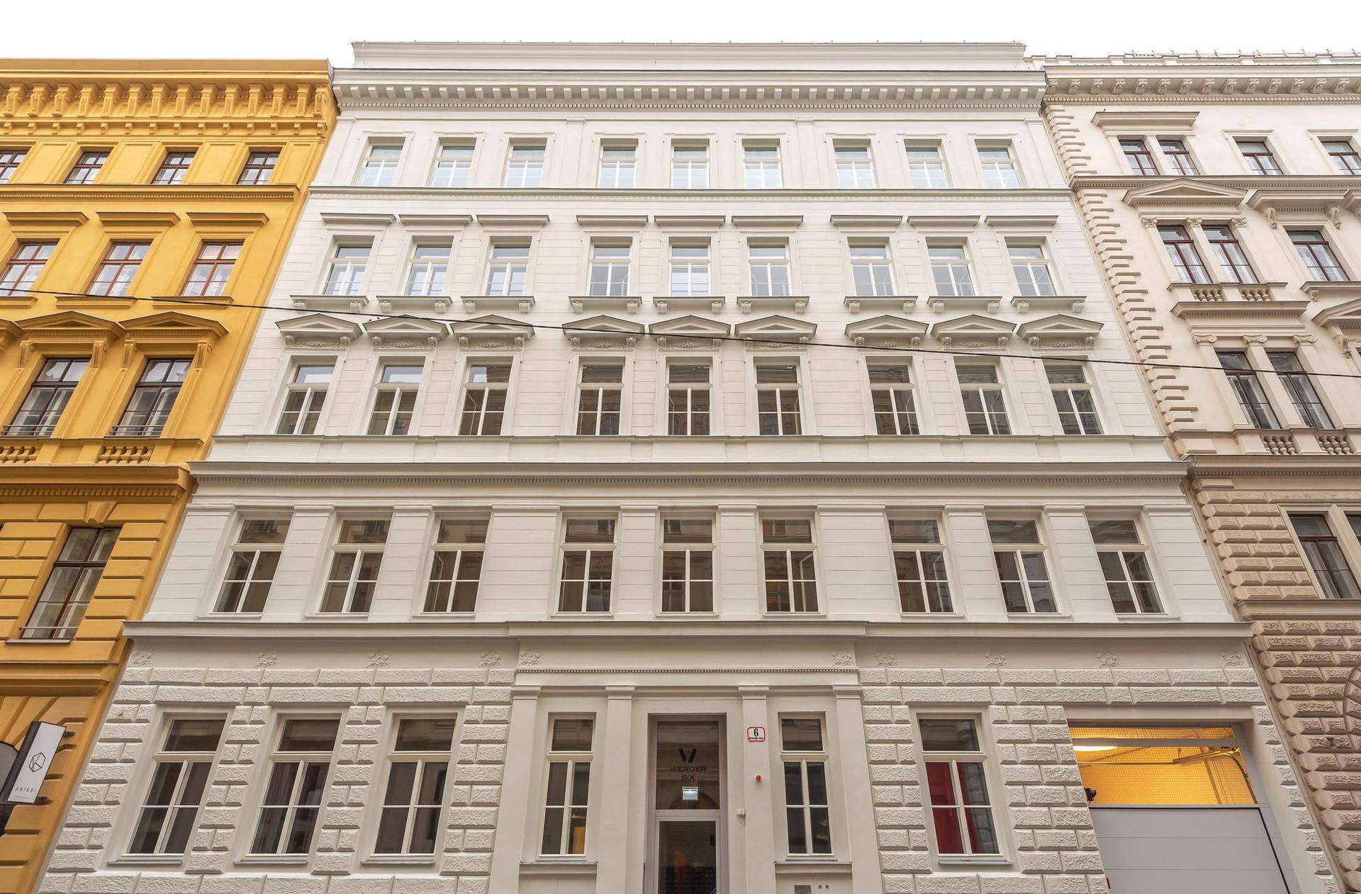 Klassische weiße Fassade eines Mehrfamilienhauses in städtischer Umgebung.