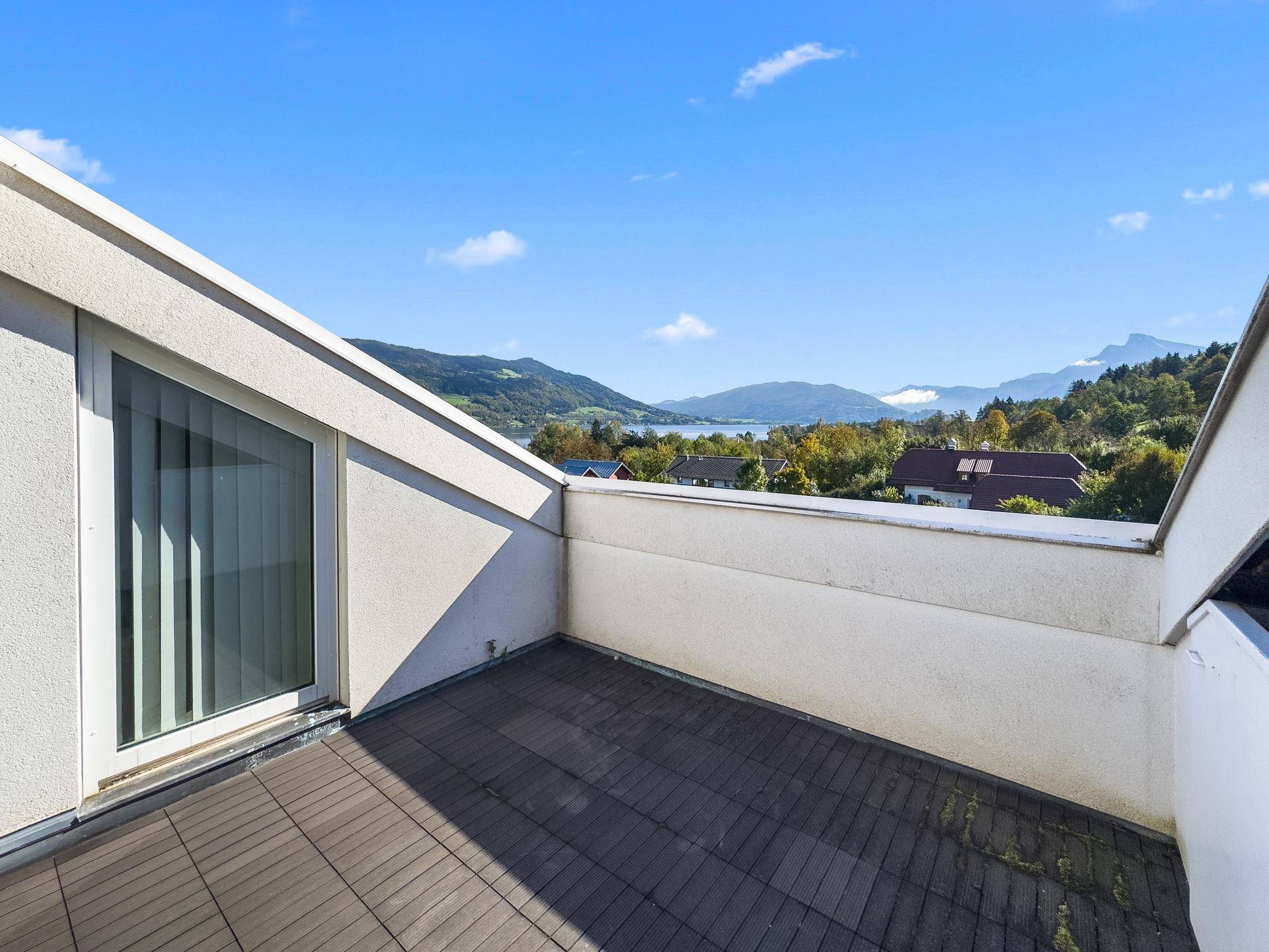 Kleiner Balkon mit Holzboden und weitem Blick auf den See und die Berge.