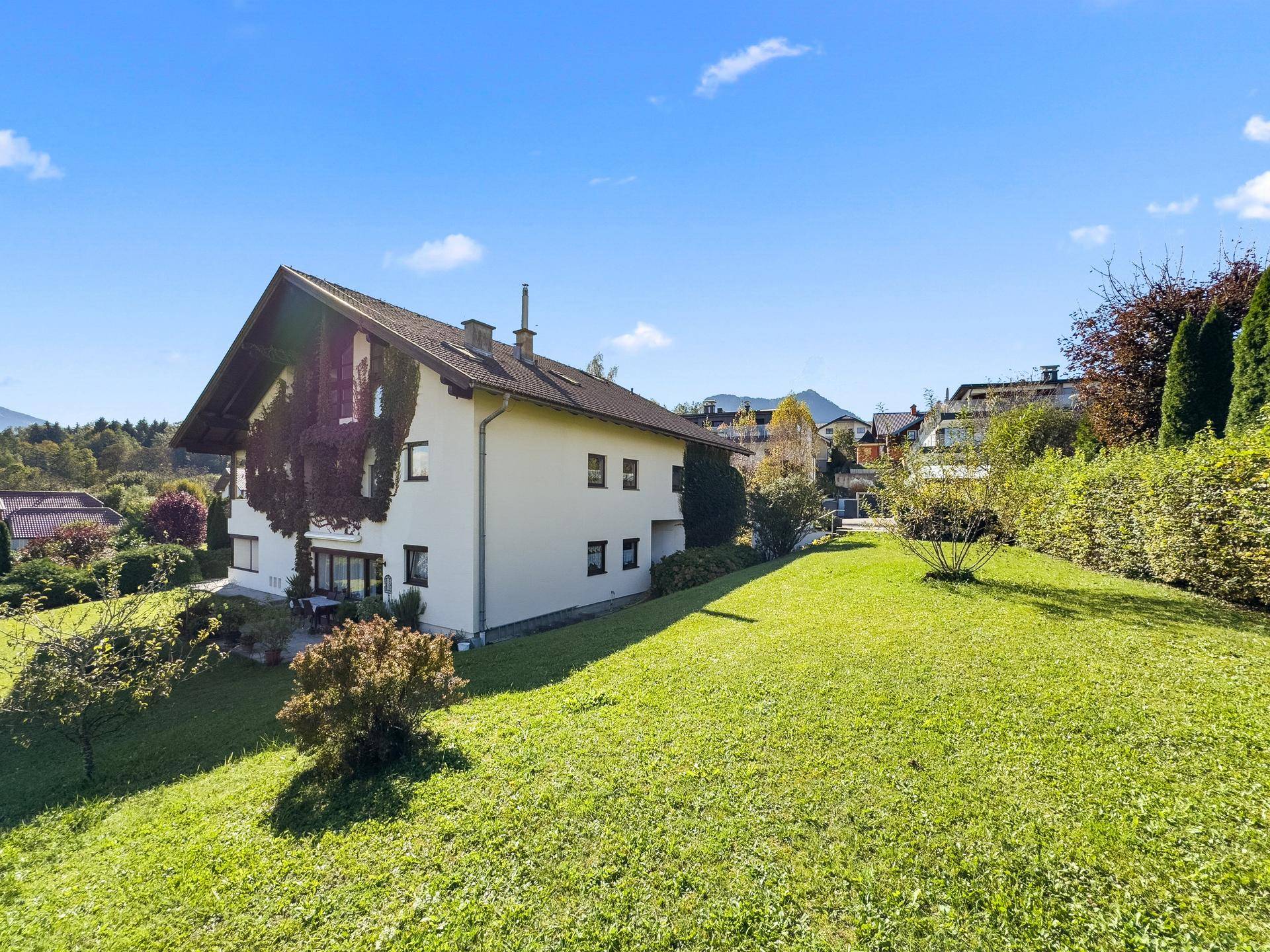 Großzügiger Gartenbereich mit Rasenfläche und einem freistehenden Haus im Hintergrund.