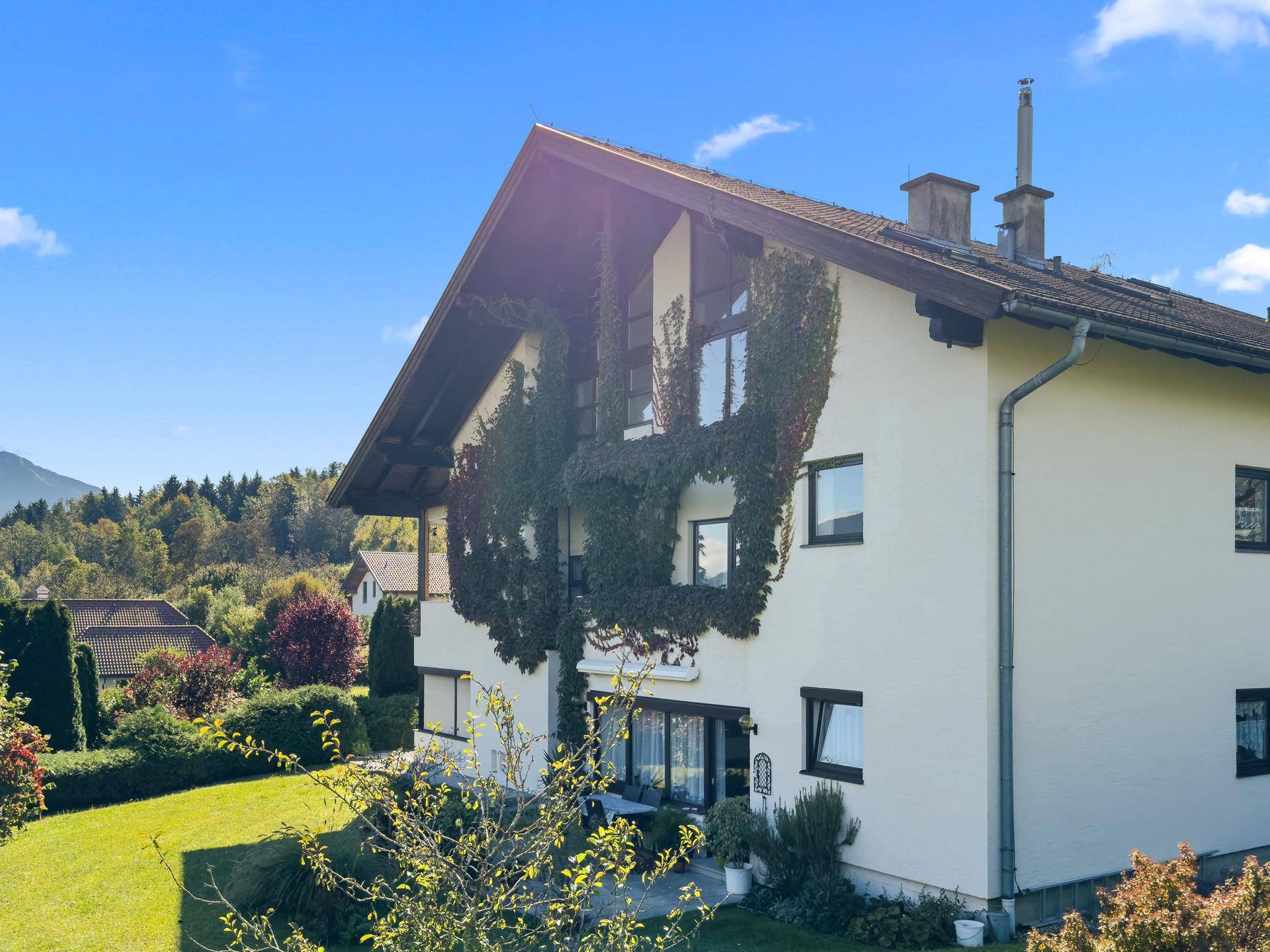 Seitenansicht eines Hauses mit bewachsenen Wänden und großzügigem Gartenbereich.