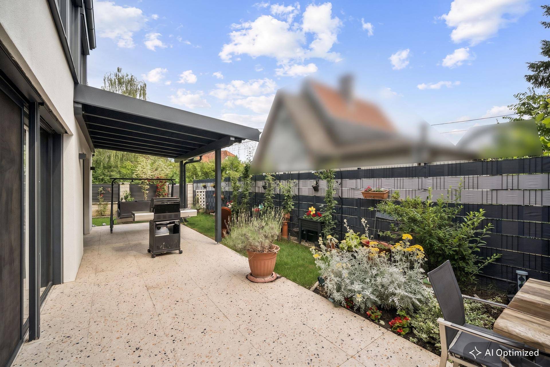 Überdachte Terrasse mit Grillbereich und Sitzgelegenheiten, umgeben von Pflanzen.