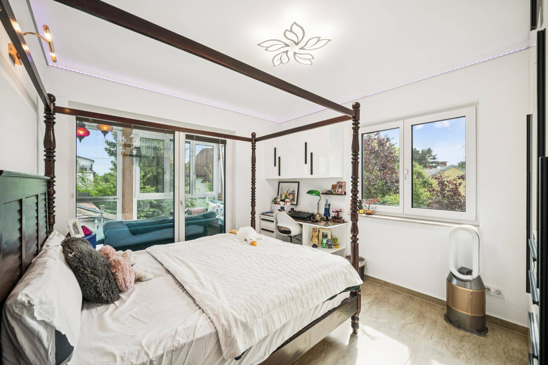 Schlafzimmer mit Himmelbett, Schreibtisch und Zugang zu einem verglasten Balkon.