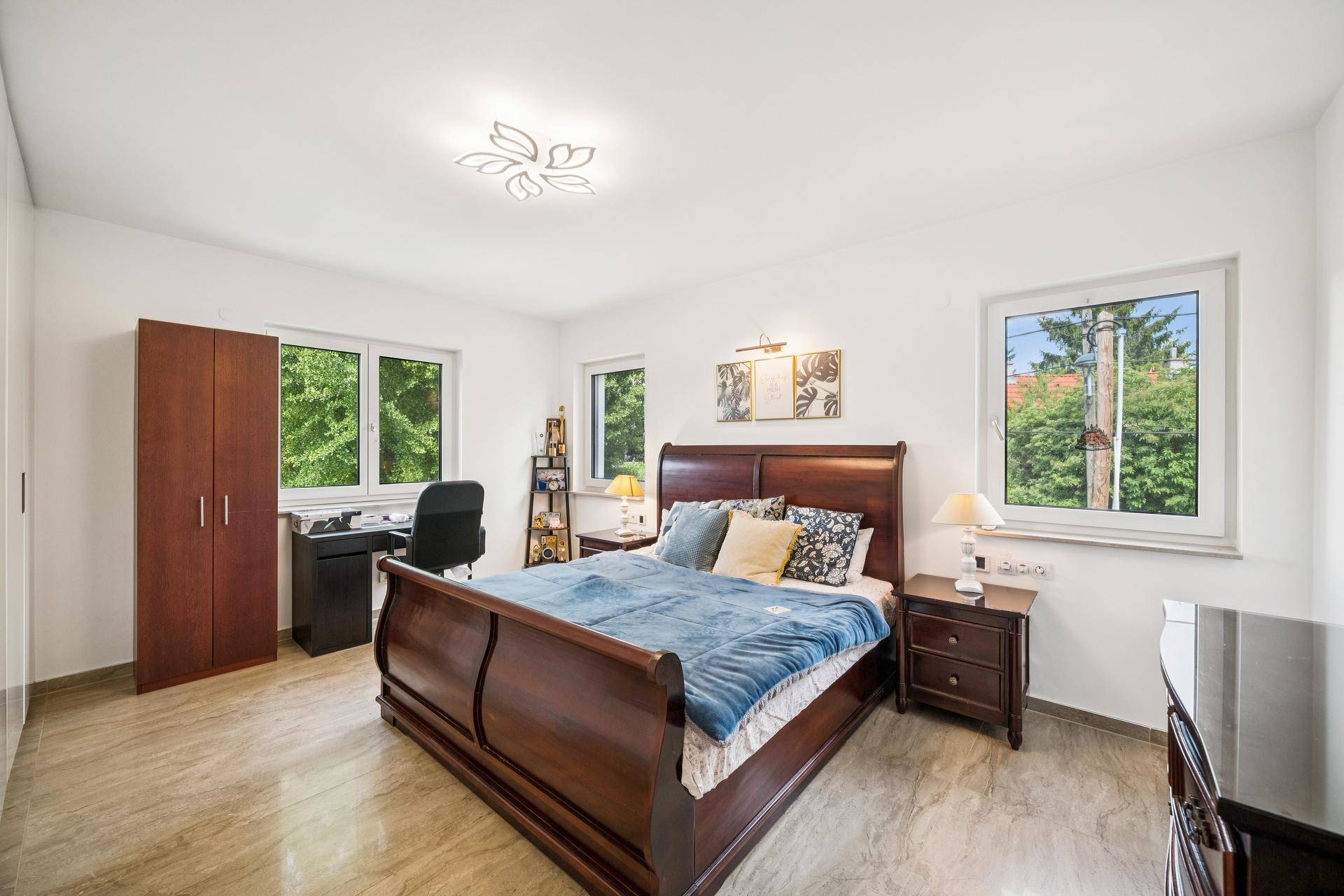 Geräumiges Schlafzimmer mit klassischem Holzbett, Schrank und Blick ins Grüne.