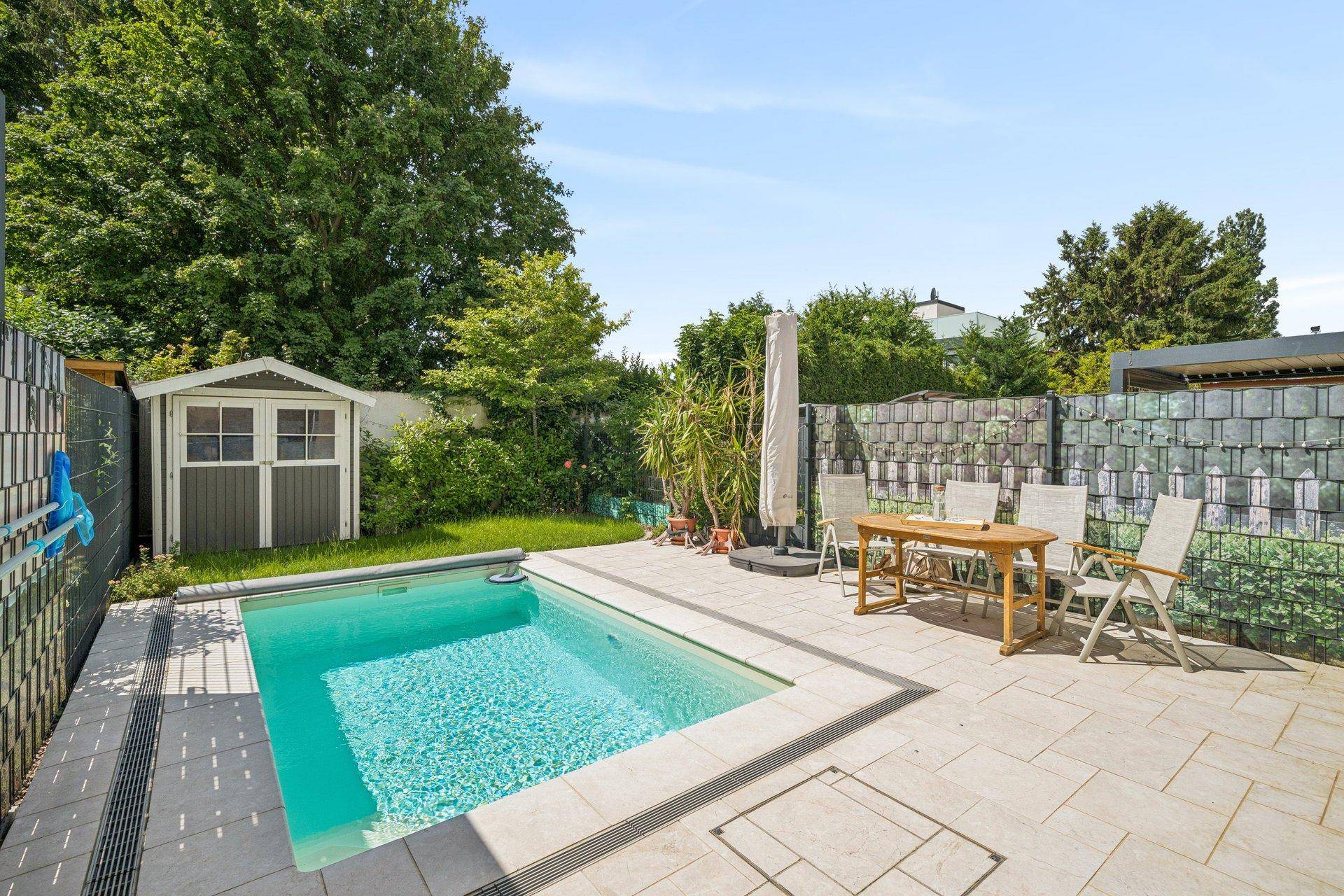 Gepflegter Gartenbereich mit kleinem Pool, Gartenhaus und gepflasterter Fläche für Entspannung im Freien.