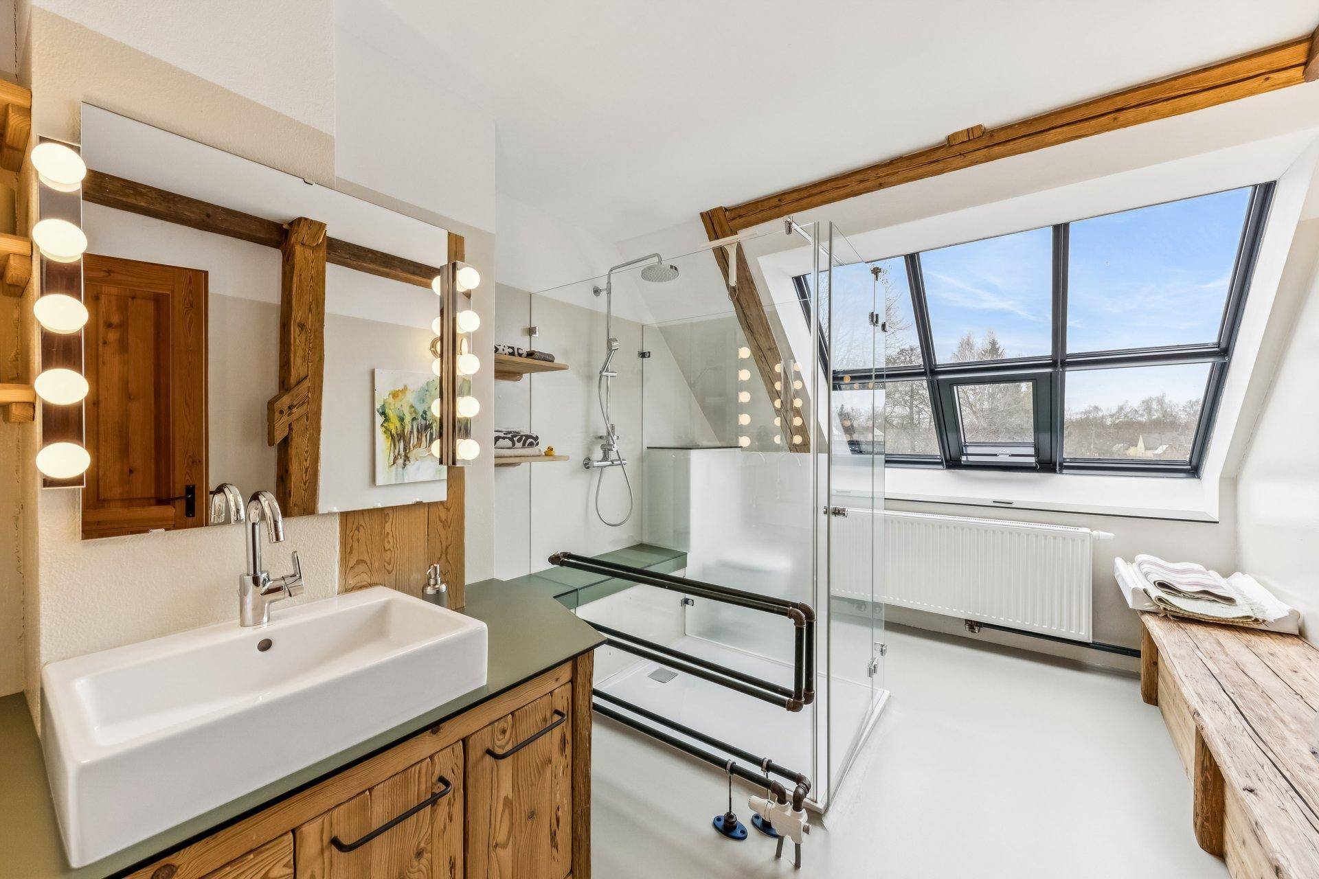 Modernes Badezimmer mit großen Dachfenstern, begehbarer Dusche und Holzelementen.