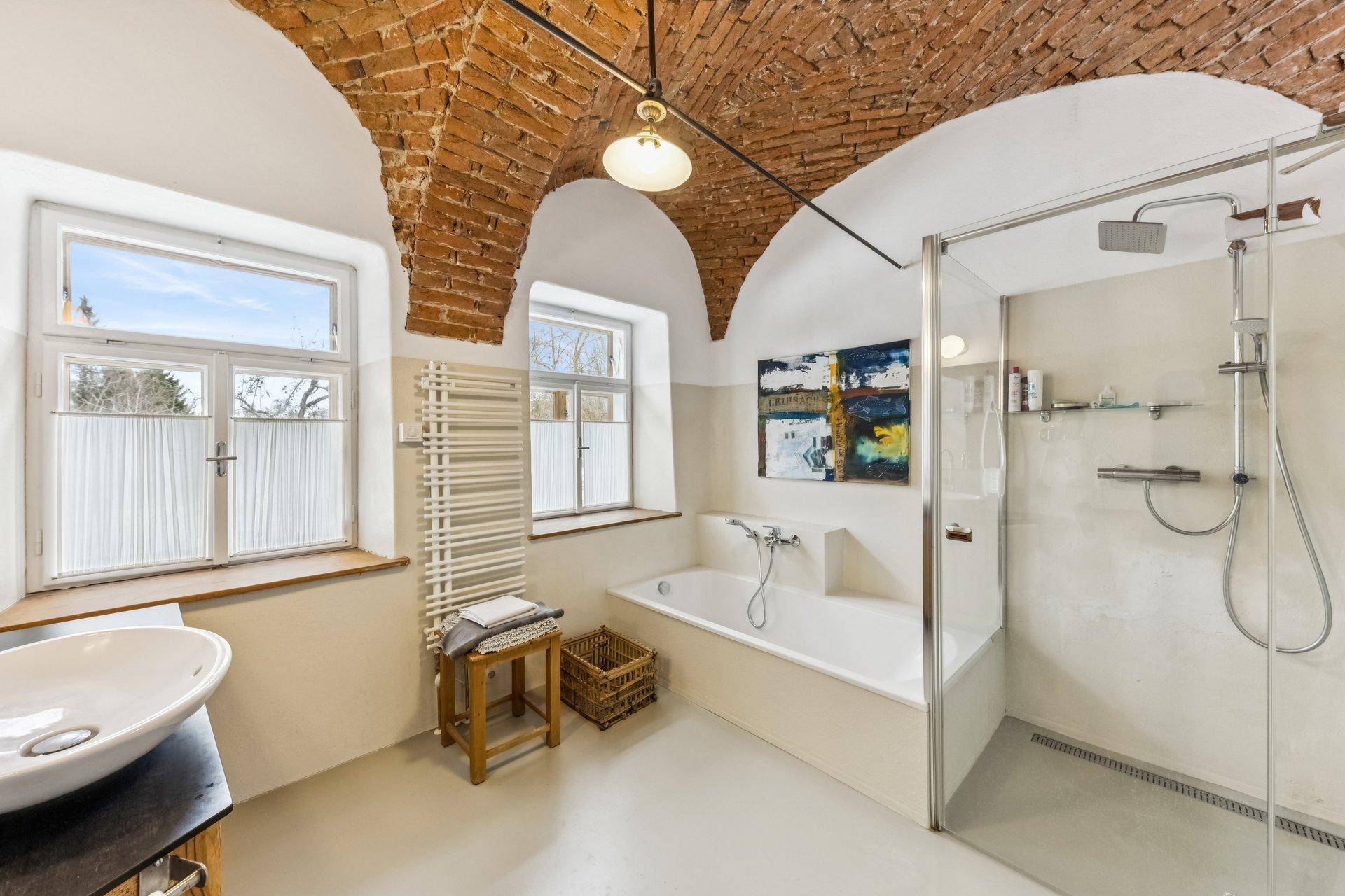 Badezimmer mit einzigartiger Ziegelgewölbedecke, Badewanne und moderner Dusche.