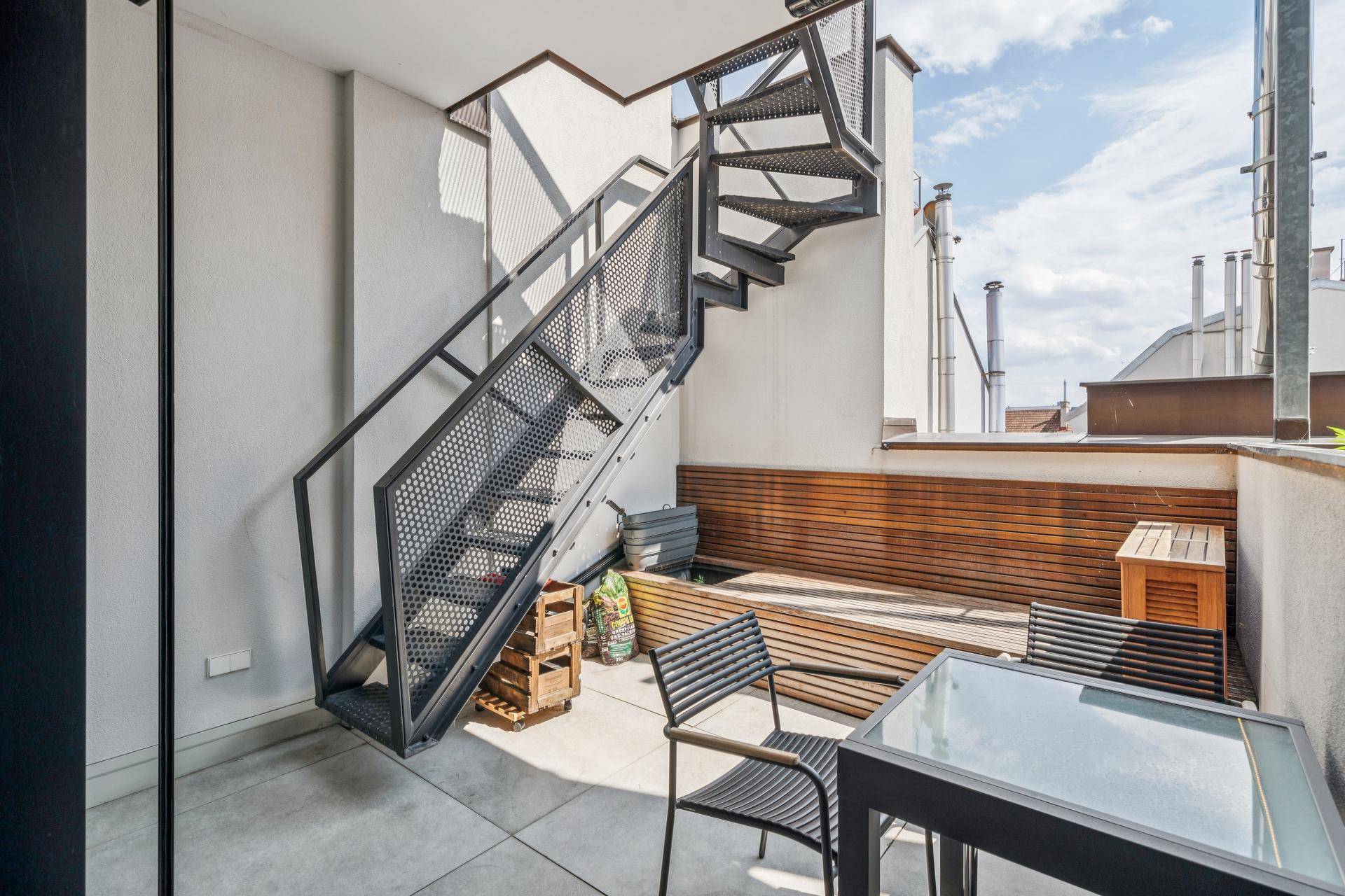 Außenbereich mit moderner Wendeltreppe und kleinem Sitzbereich auf dem Balkon.