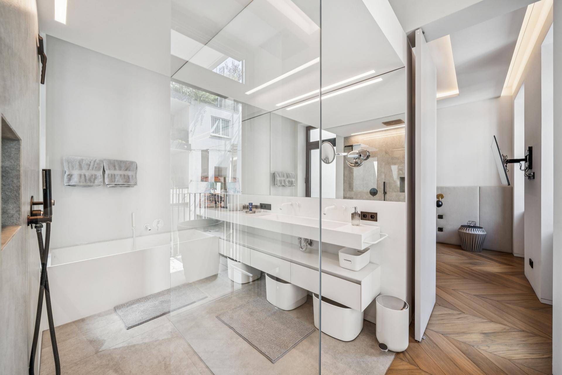 Luxuriöses Badezimmer mit Doppelwaschtisch, Badewanne und großer Spiegelfläche.