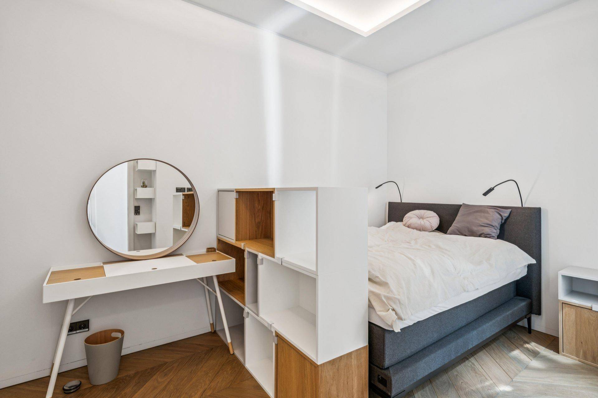 Helles Schlafzimmer mit modernem Bett, Schreibtisch und Parkettboden.