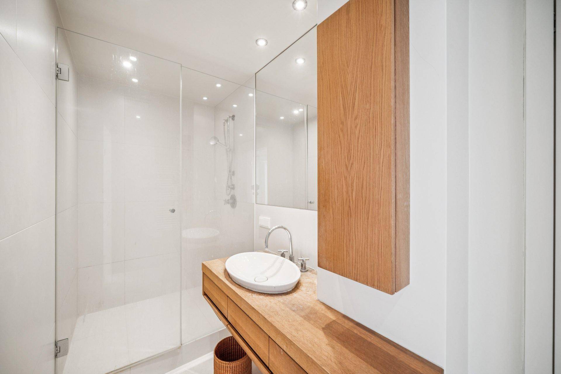 Modernes Badezimmer mit begehbarer Dusche, Holzwaschtisch und minimalistischem Design.