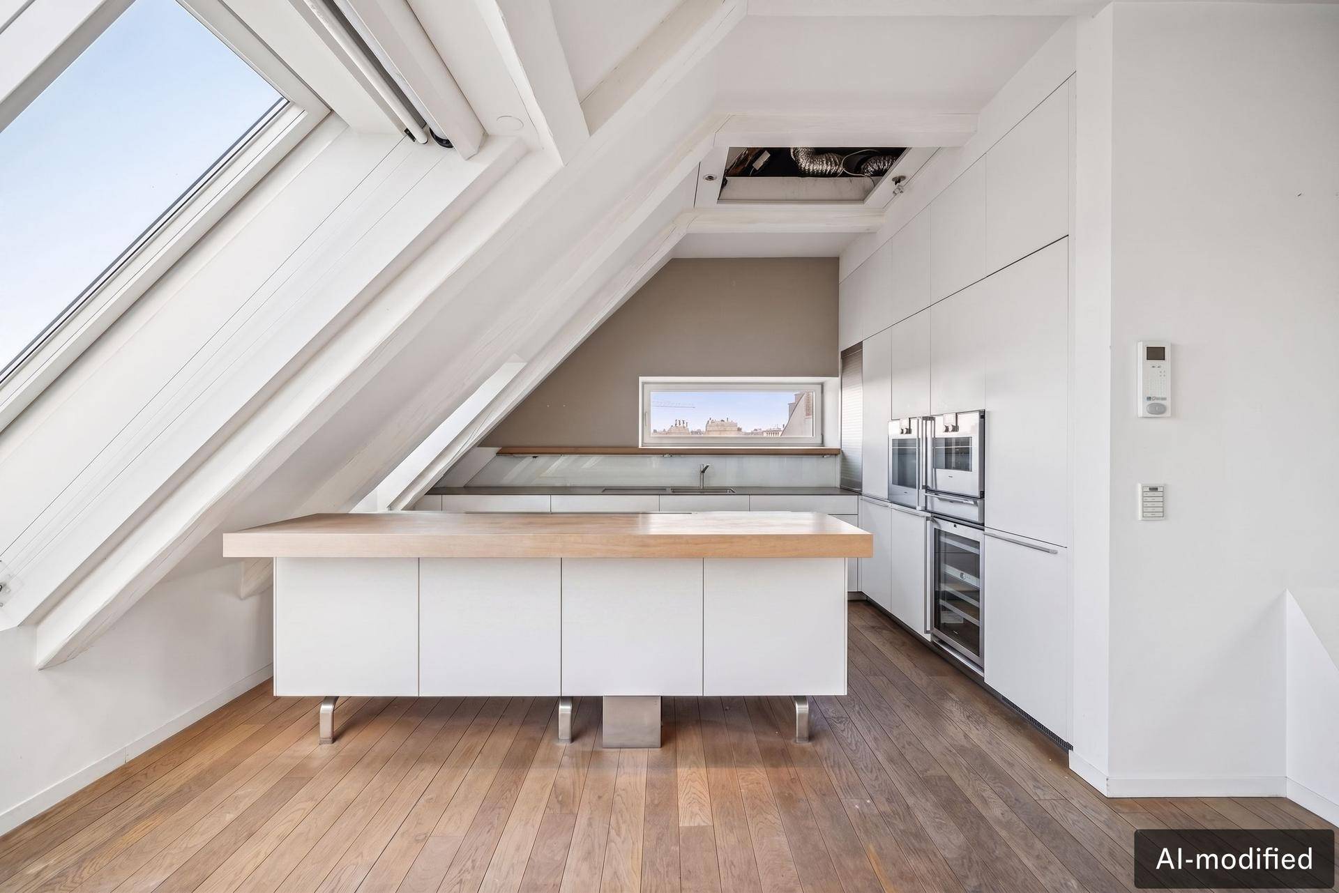 Moderne Einbauküche im Dachgeschoss mit weißen Schränken, Holztheke und Dachfenstern.
